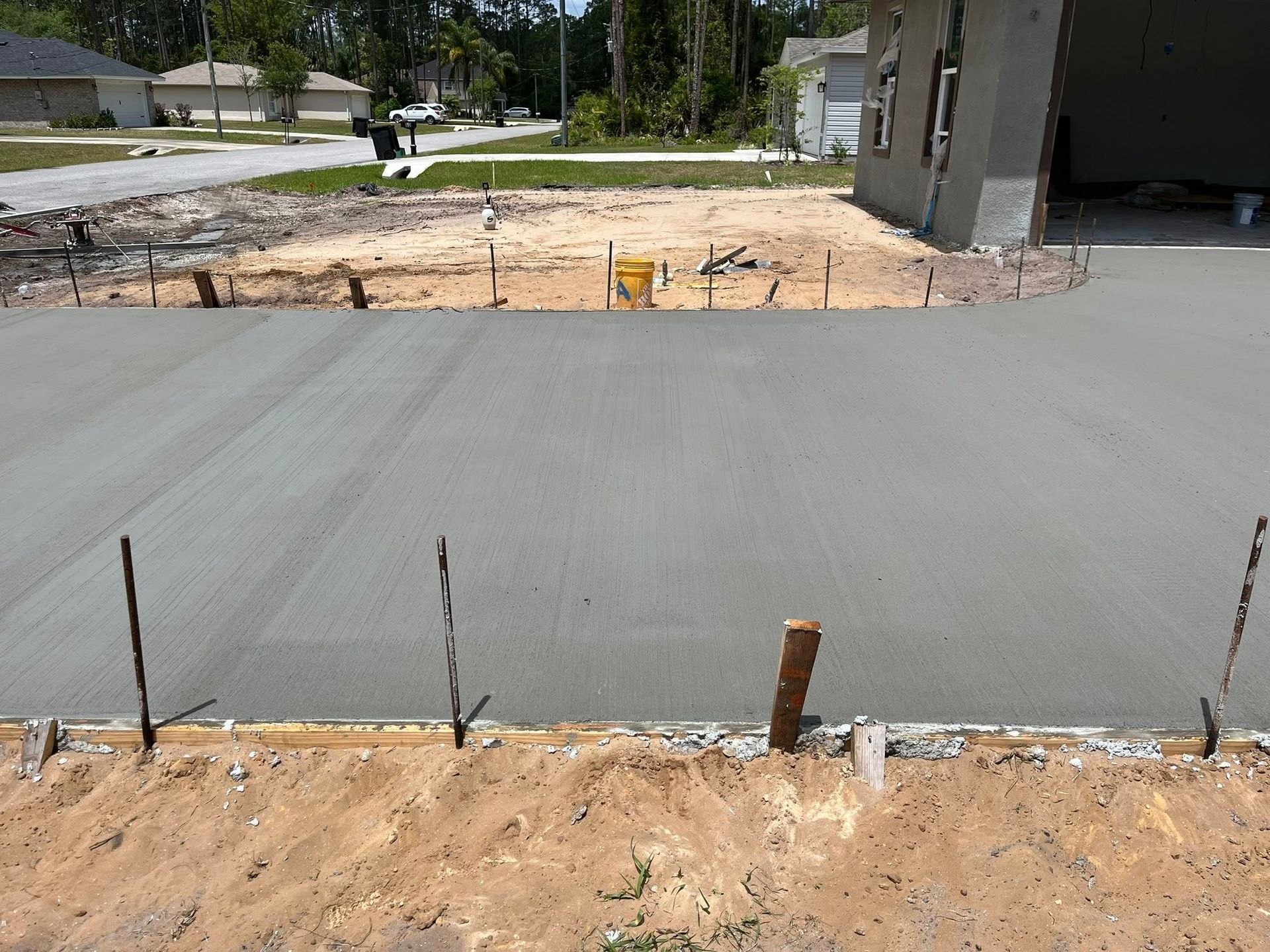 Freshly poured concrete driveway in front of a house under construction.