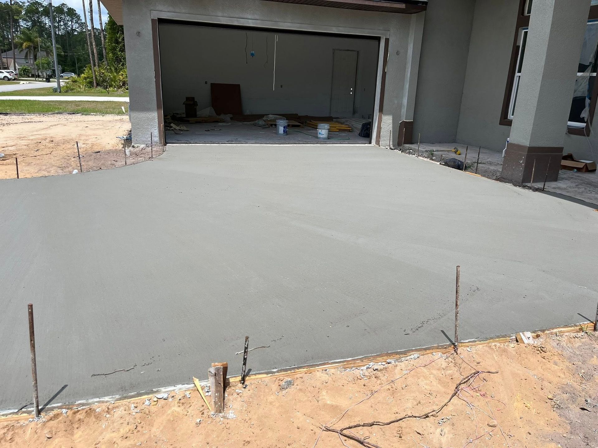 Freshly poured concrete driveway in front of a house under construction.