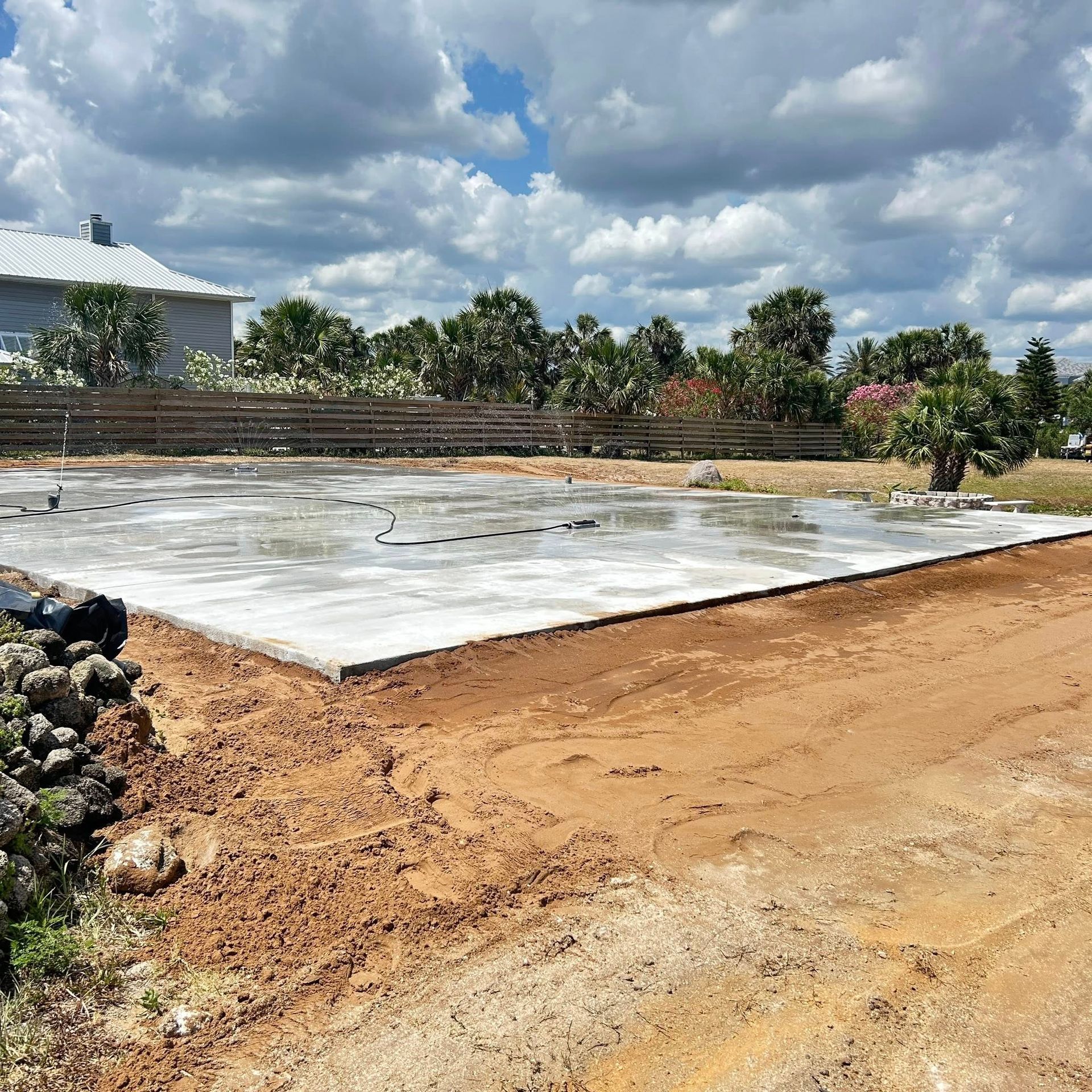 Concrete foundation on dirt, prepared for building, under a cloudy sky.