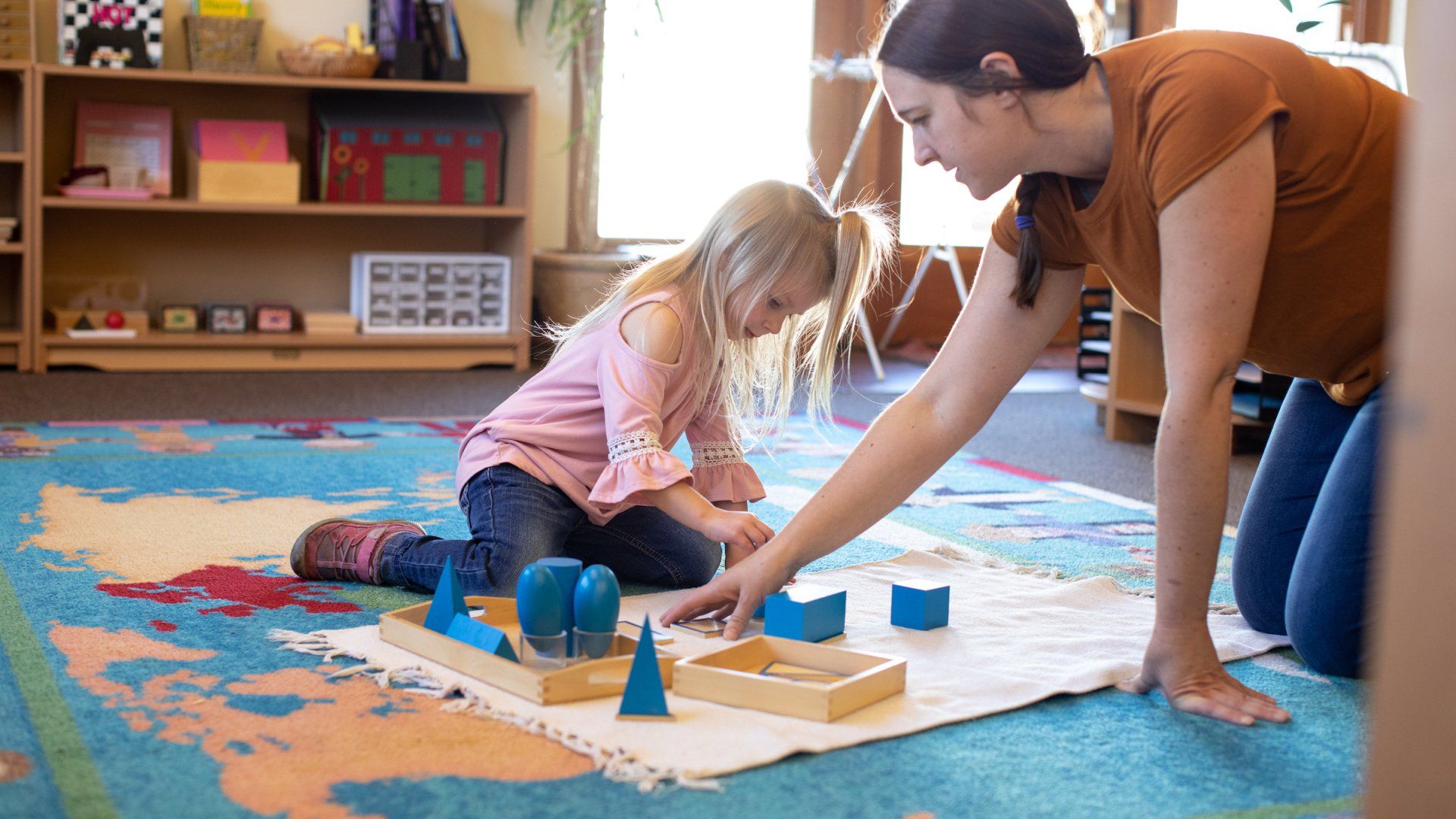 Guide and child workin with the Montessori geometric figures. 