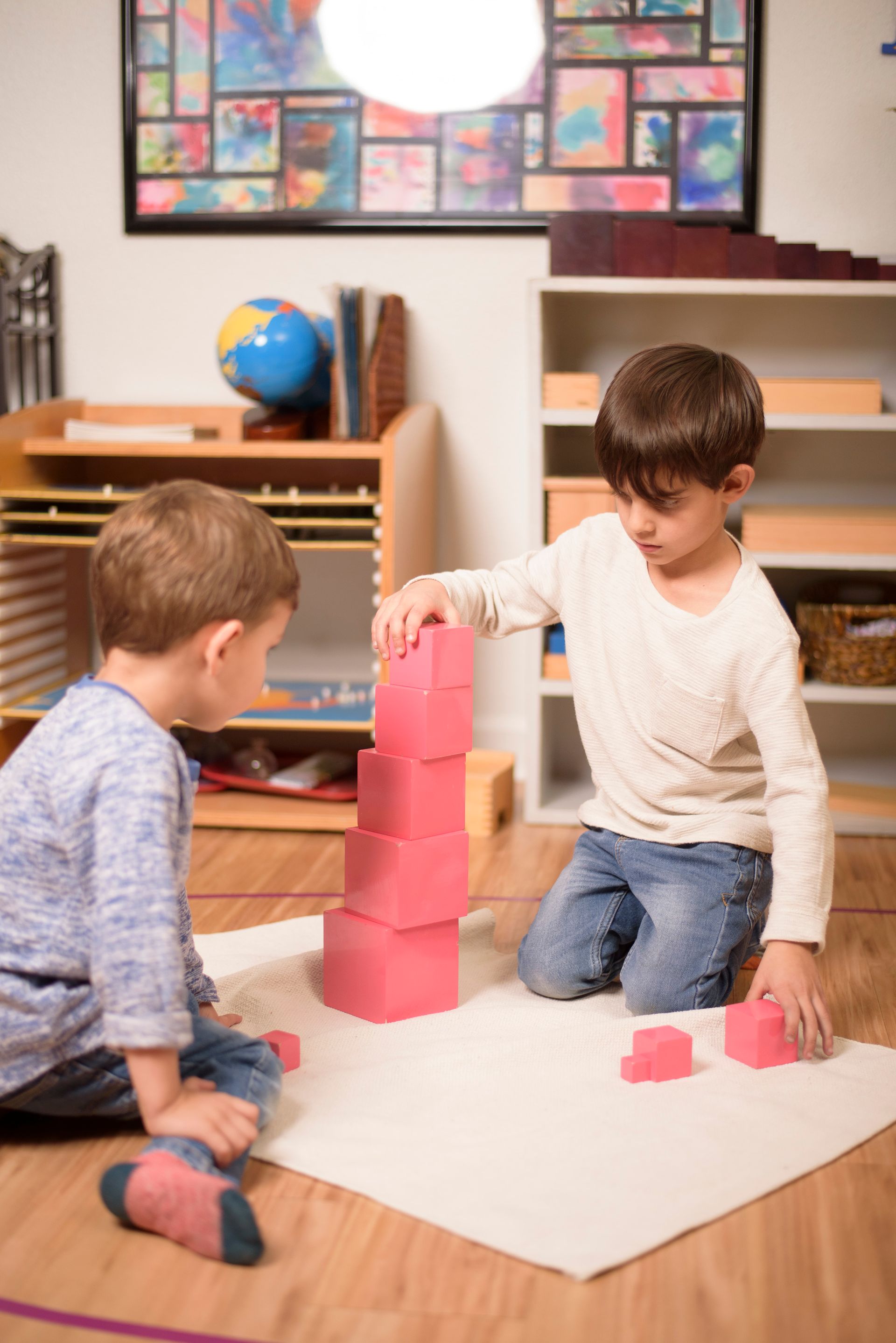 Montessori children working together with the pink tower