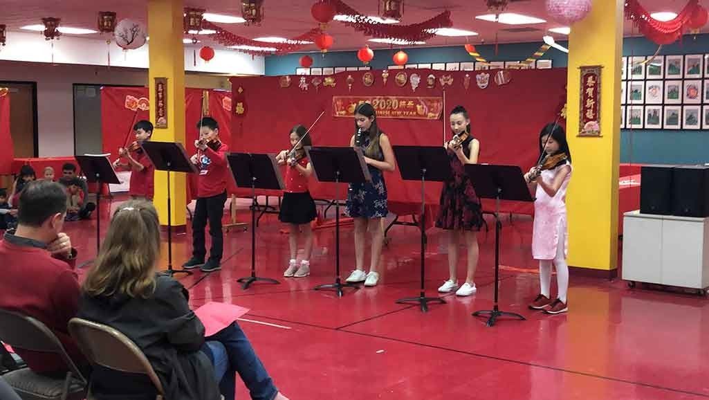 A group of Montessori elementary students play violins and woodwind instruments during a Chinese New Year school concert performance.