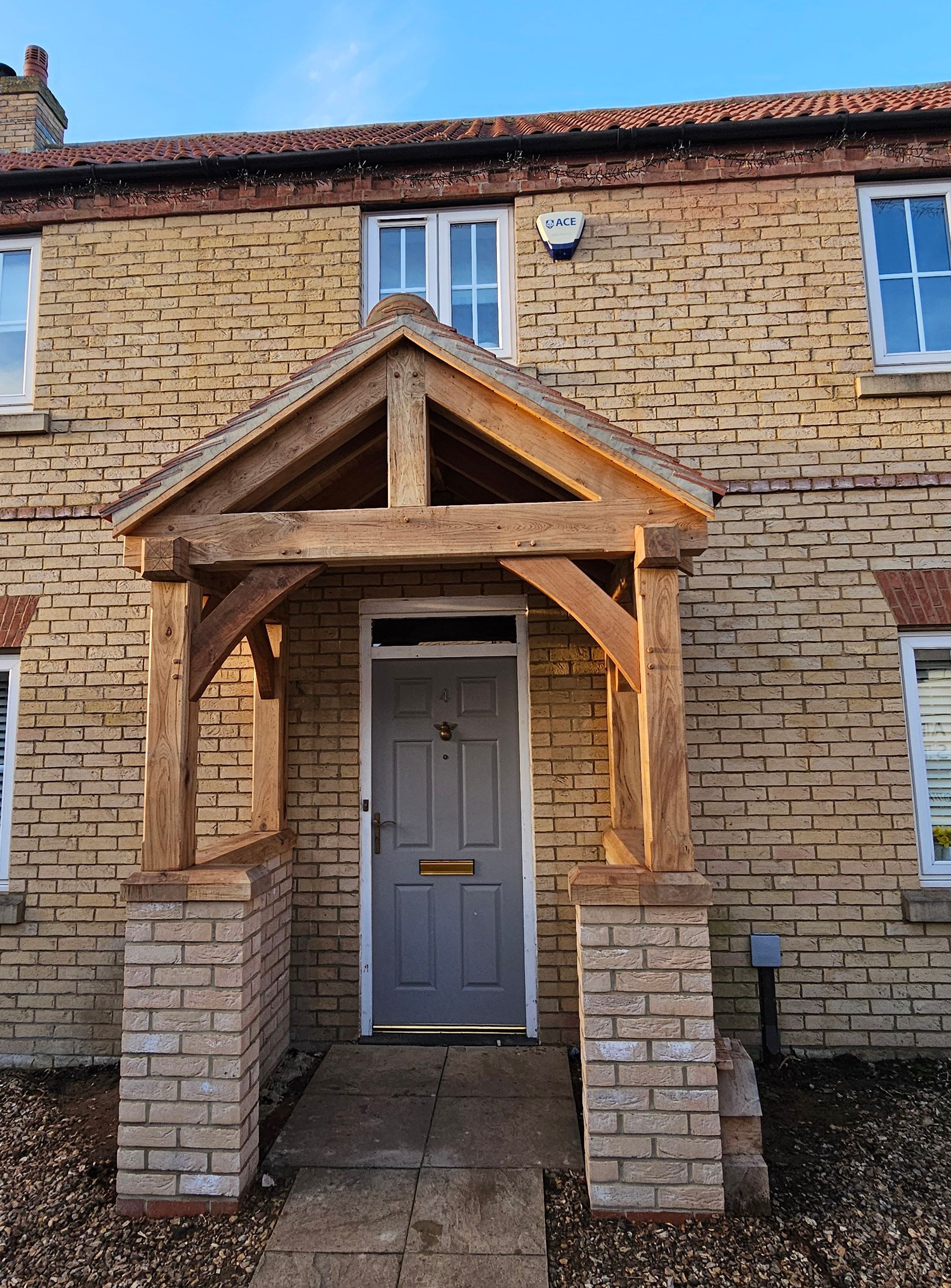 A rustic house exterior with a grey front door, oak porch frame.