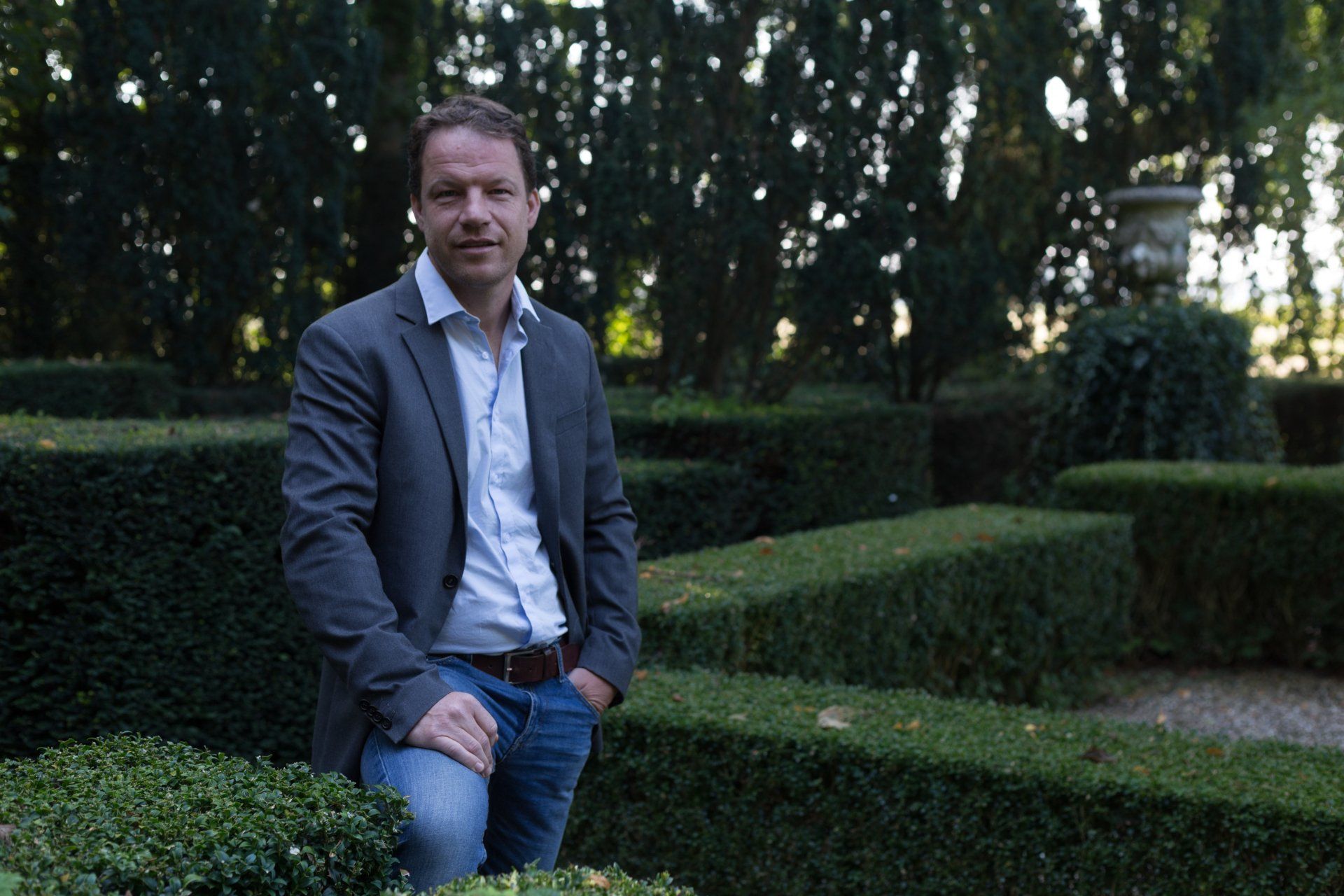 Christian Kolk staat bij de geschoren heggen in de voortuin van Oosterhouw KTK