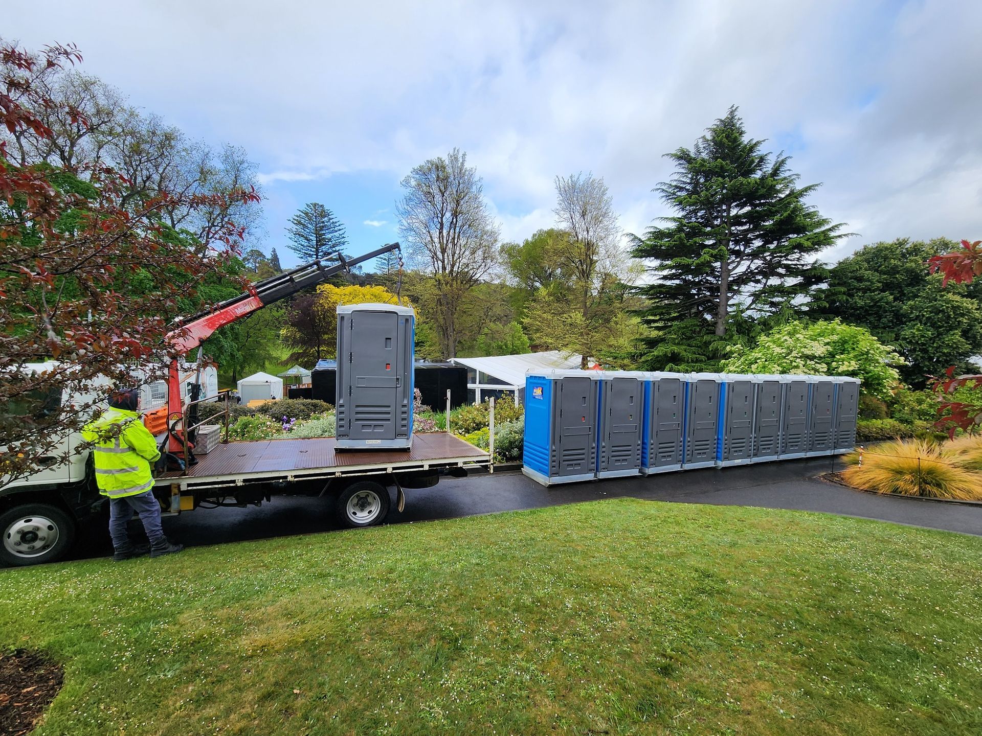 Worker Unloading Portable Toilets from A Truck in A Park-Like Setting — Wee R Portable Loos in Glenorchy, TAS