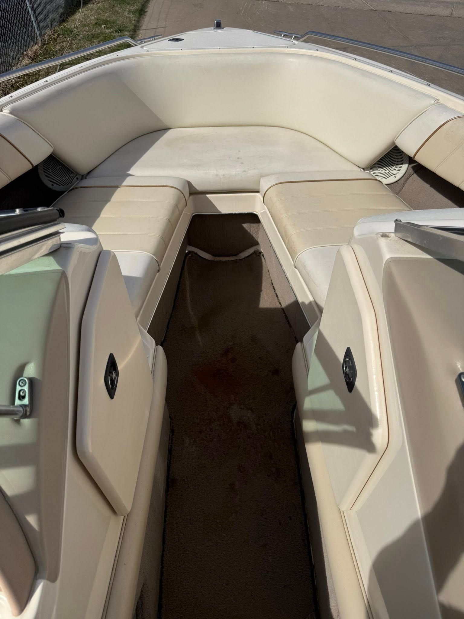 Tan upholstered boat seating area with a center walkway and tan cushions on both sides