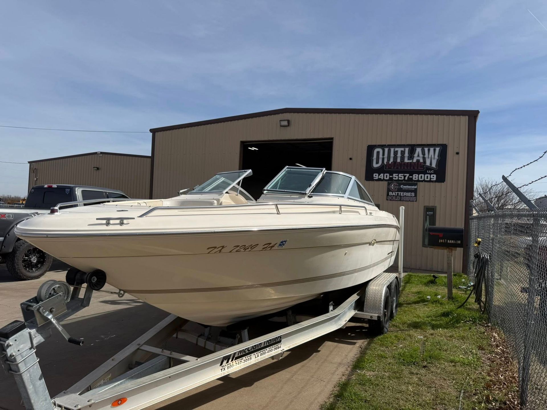 White speedboat on a trailer outside a boat shop on a sunny day