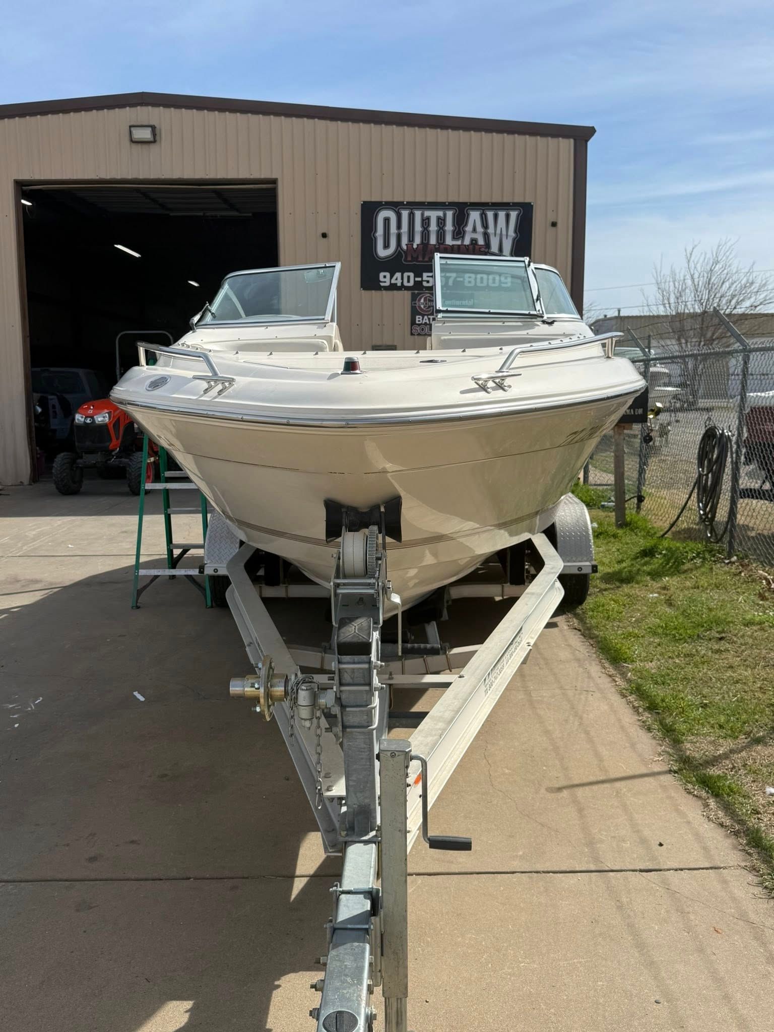 White motorboat on a trailer in front of a boat shop garage entrance