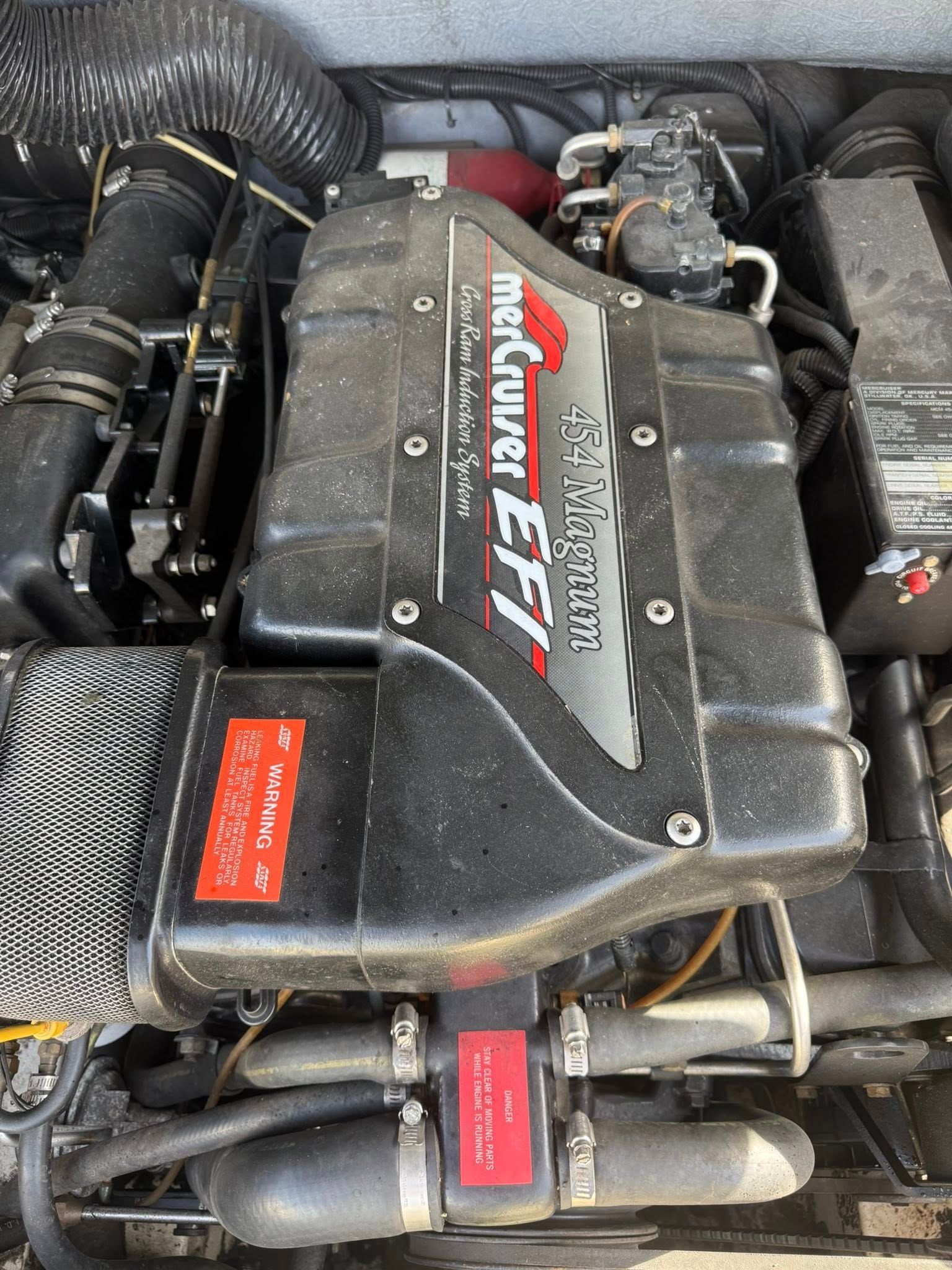 Close-up of a car engine bay with a large black engine cover labeled “Mercury EFI”