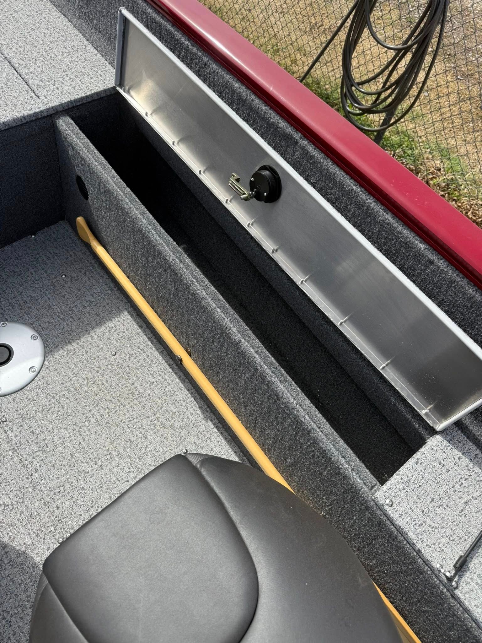 Roof deck storage compartment with open lid, gray carpet, and visible wiring