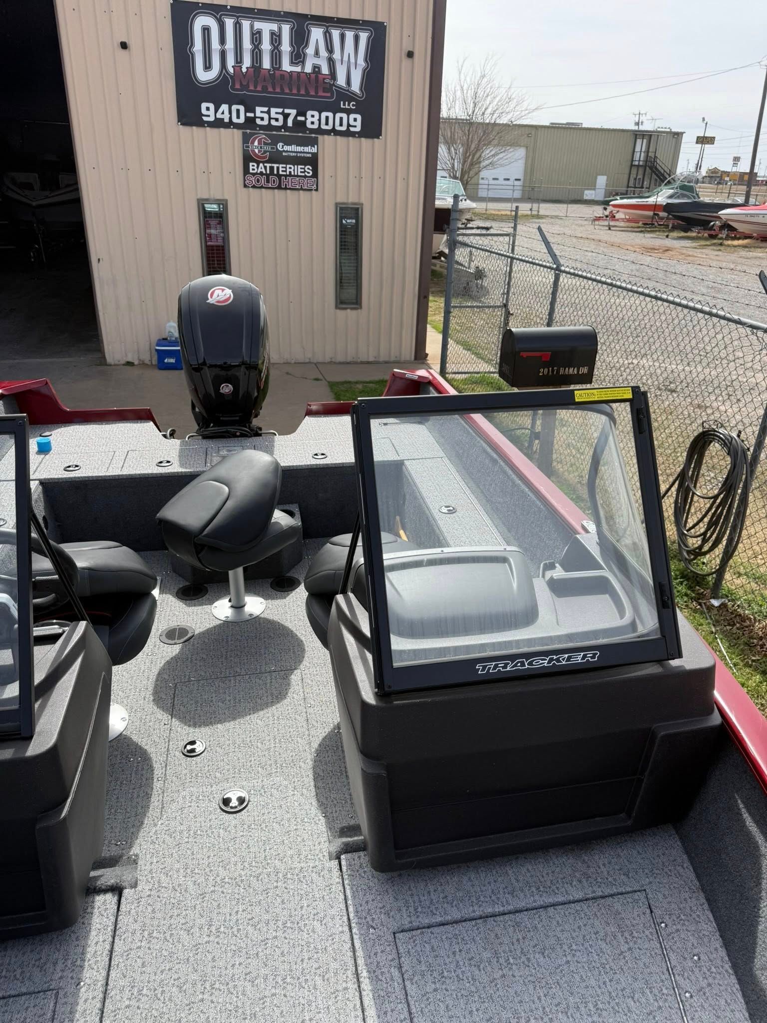 Outdoor lot with a black display cooler and grill parts beside a building labeled 