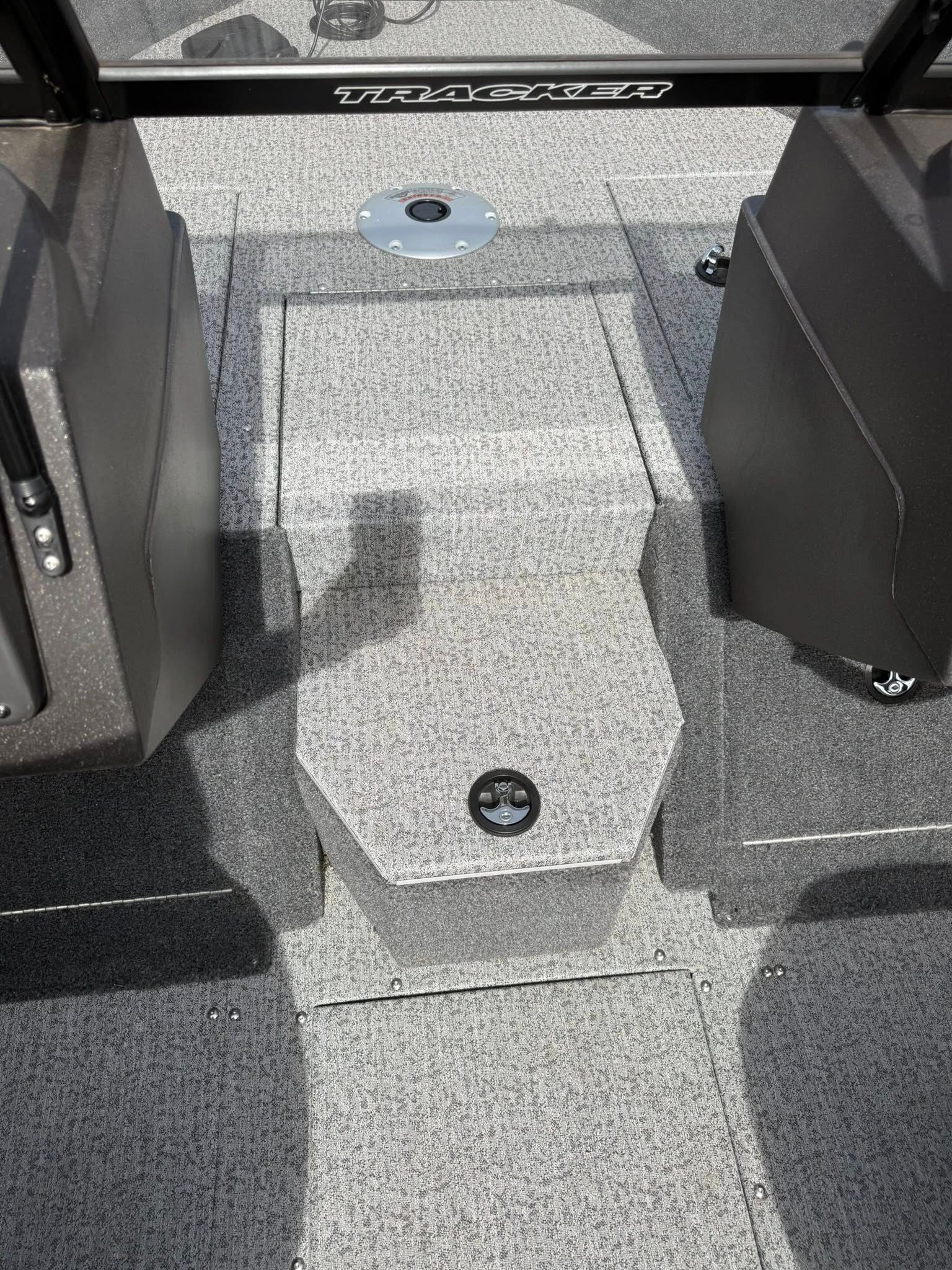 Gray carpeted boat deck with a central hatch and black seating on both sides