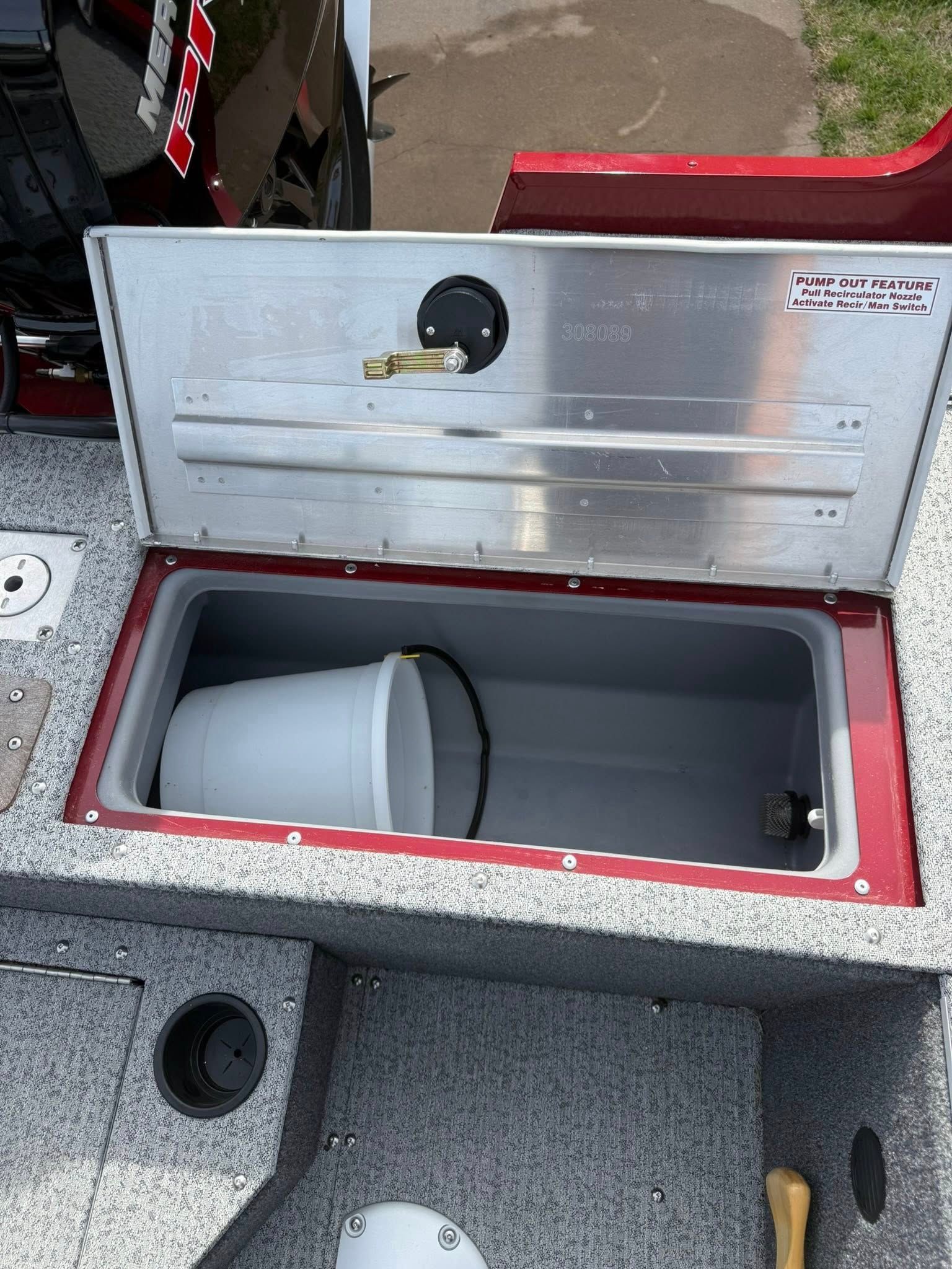 Open cooler with a white bucket inside on a speckled boat deck.