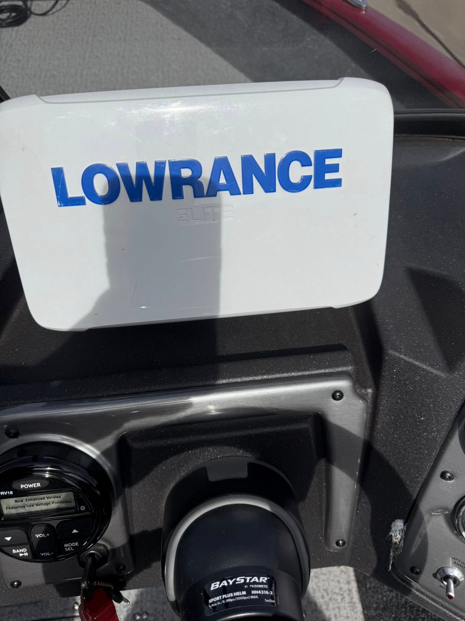 Lowrance fish finder screen mounted on a boat console, with a white cover above it