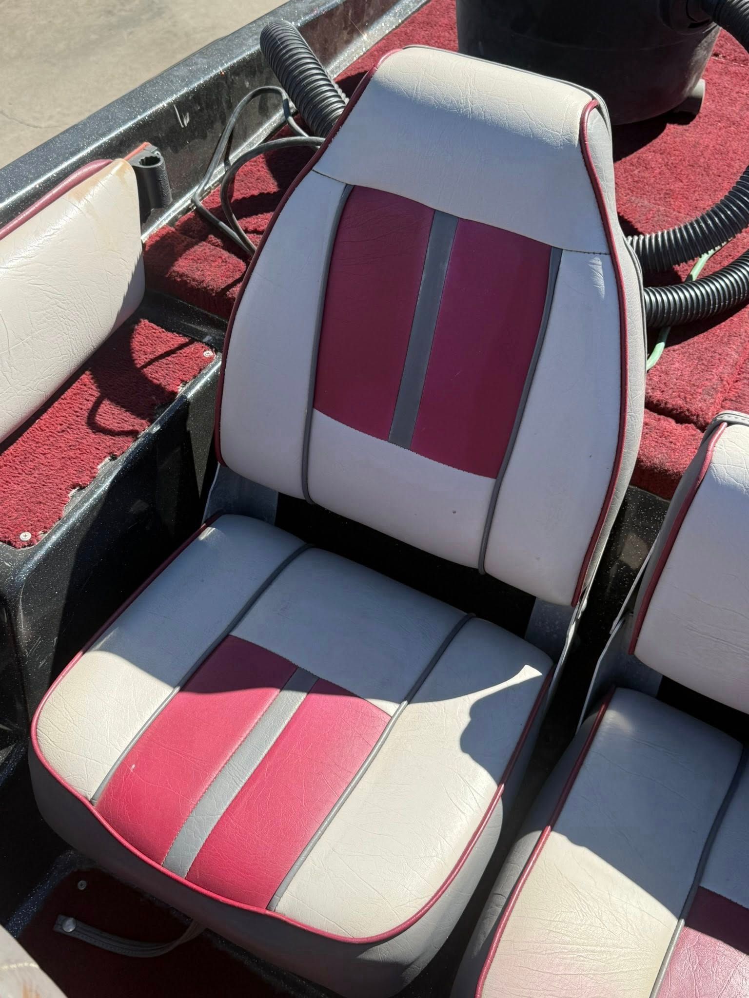 Red and white padded boat seat with striped center panels on a red deck