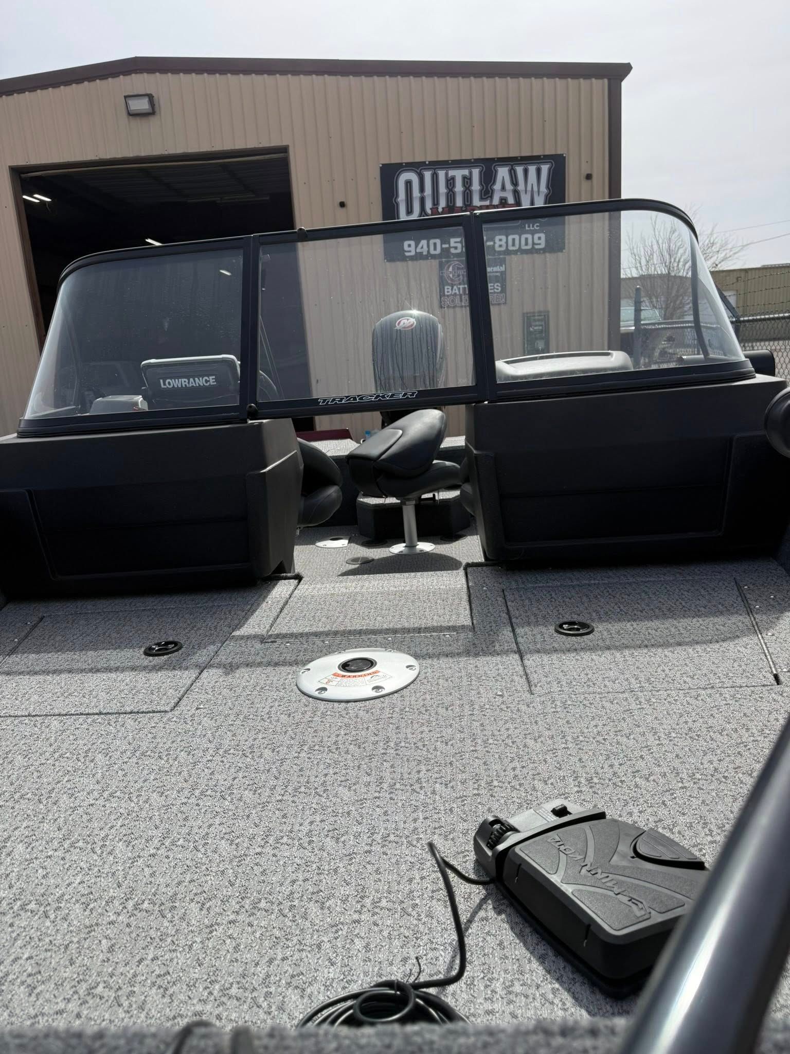 Outlaw shop entrance with black seating and glass windbreaks on a gravel lot