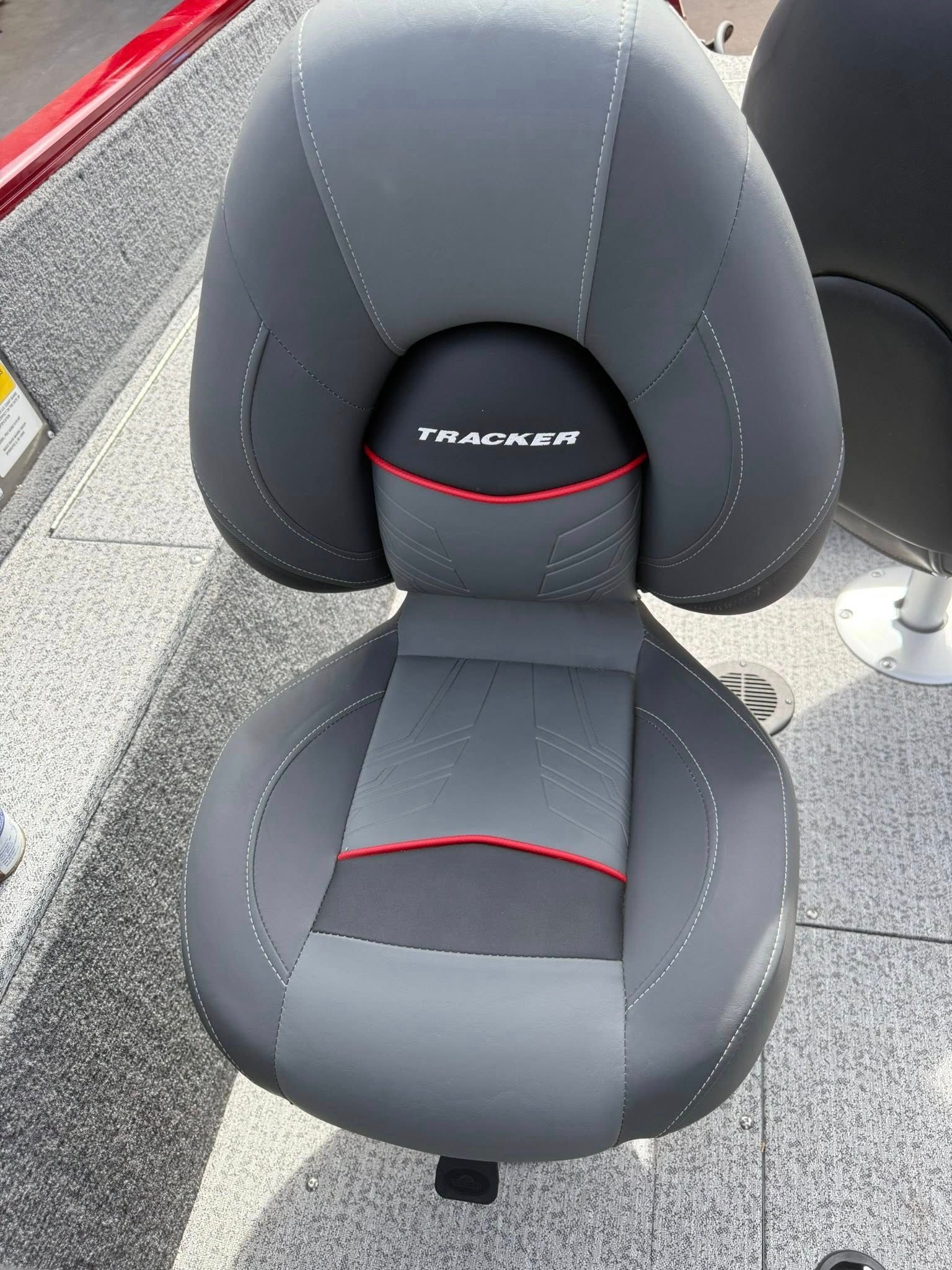 Black and gray Tracker boat seat with red accents, shown outdoors on a dock or boat deck.