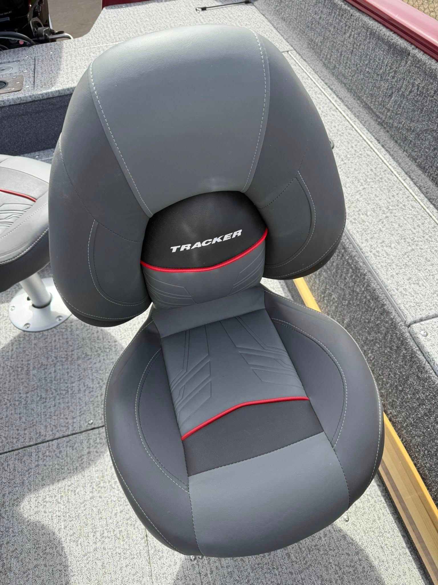 Black and gray fishing boat seat with red accents and white logo on a deck outdoors