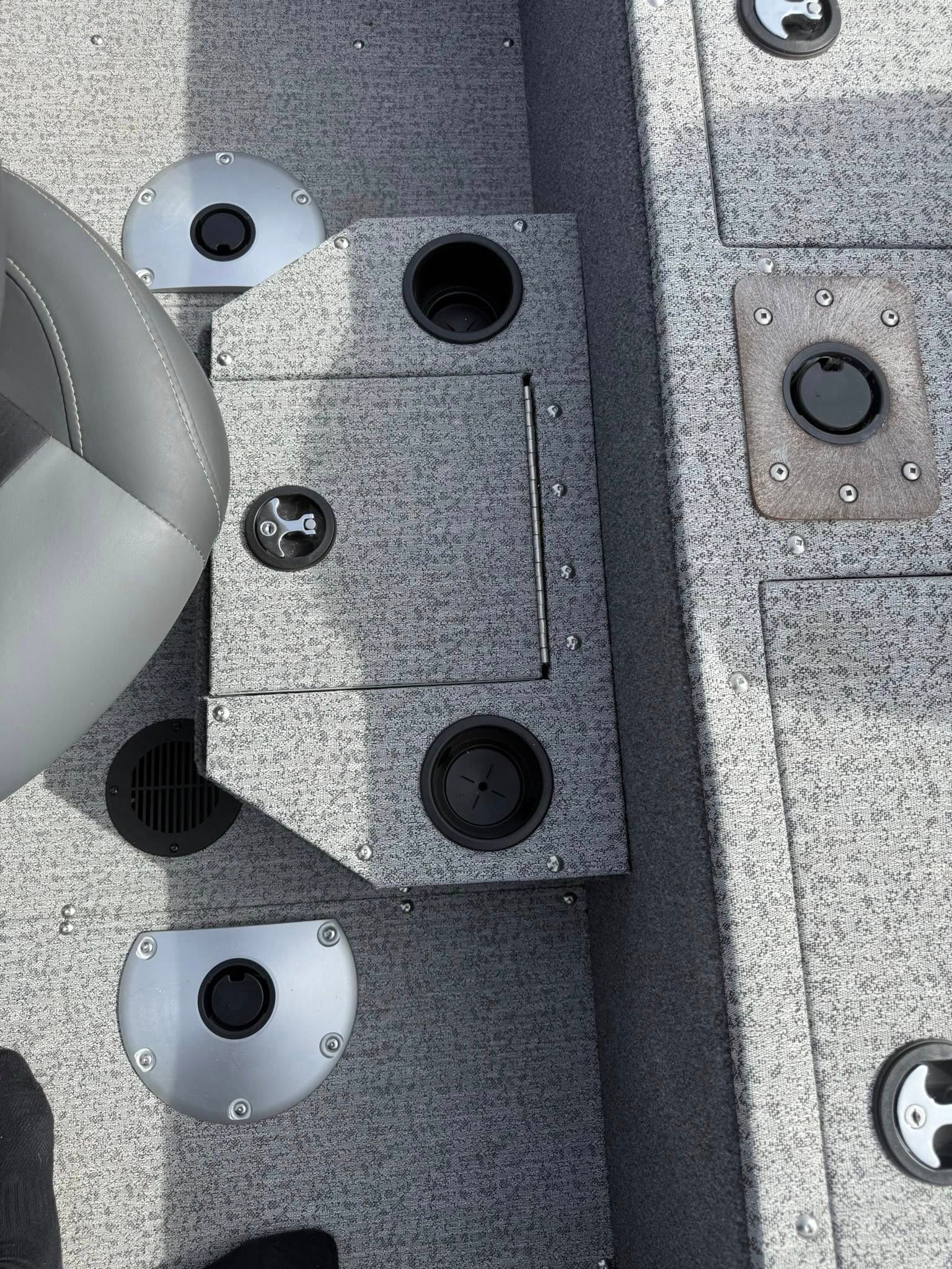 Close-up of gray textured metal hardware with black screws and circular holes on a boat or machine surface