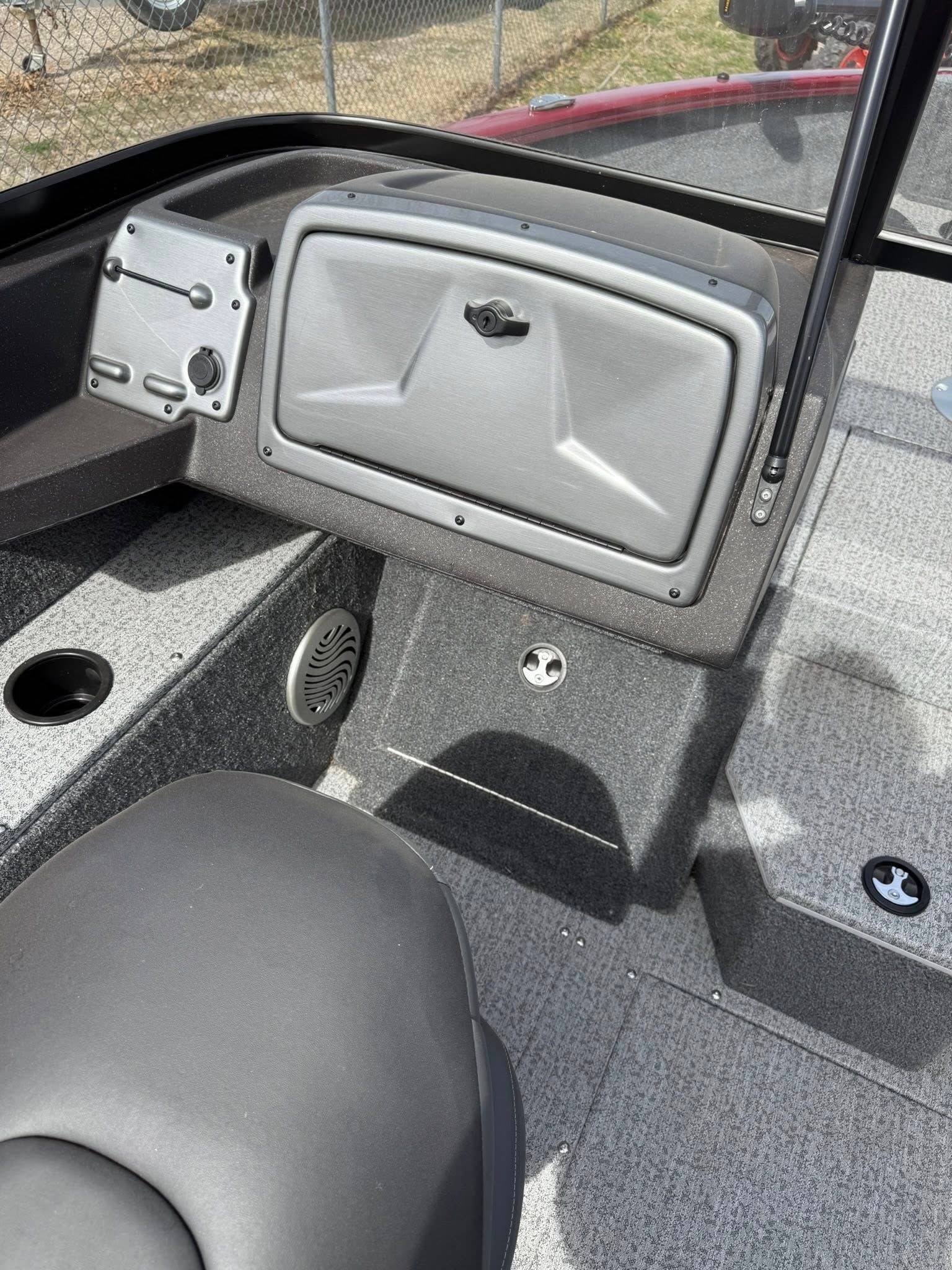 Gray boat cabin with a small hatch door and seating area next to a window.