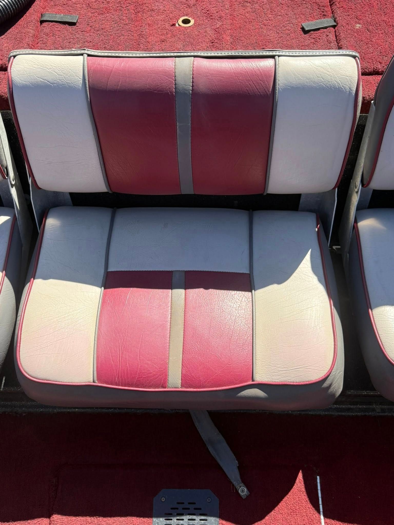 Two-tone red and white boat seats on a red carpeted deck, viewed from above