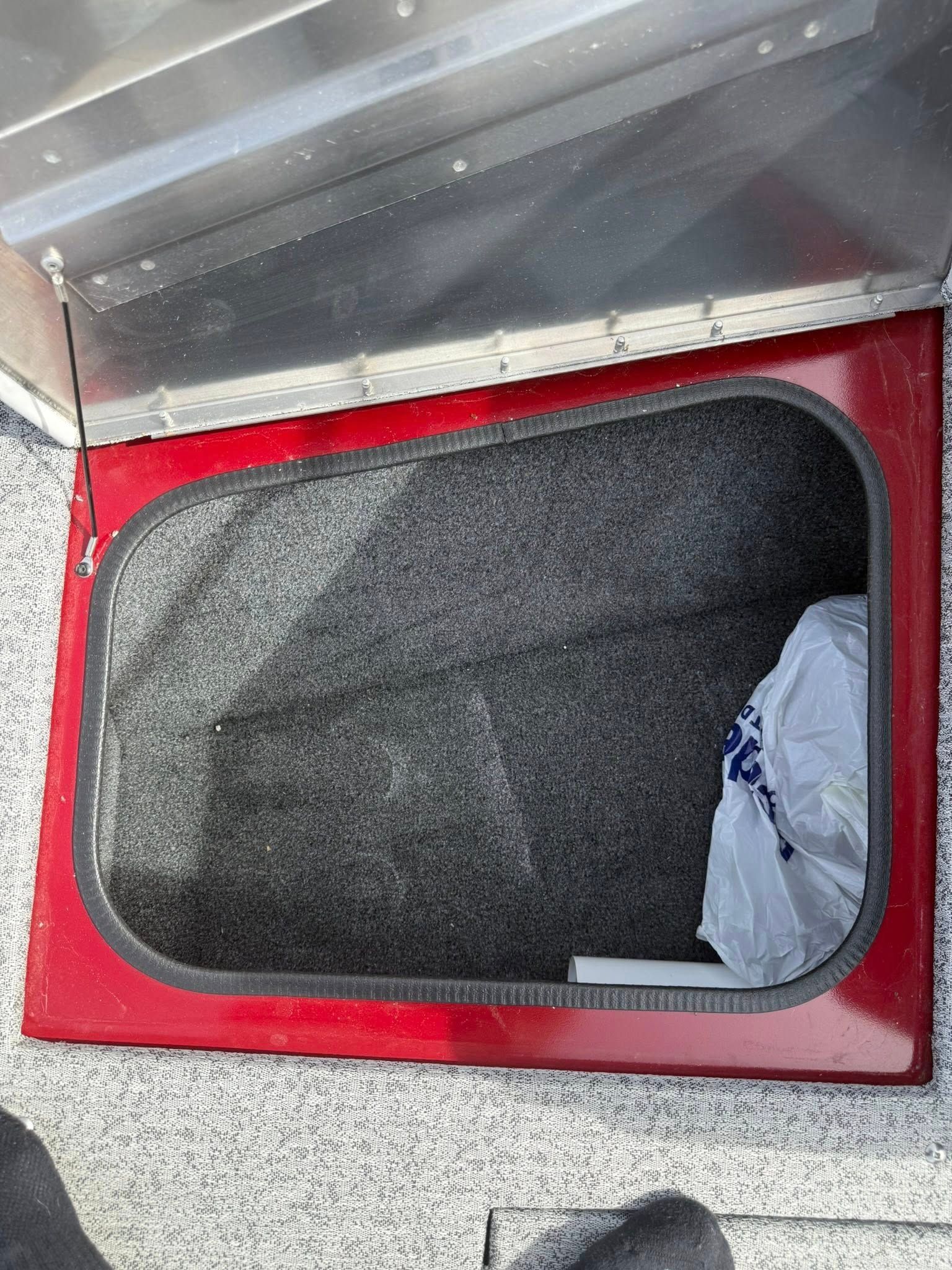 Open red floor hatch with a dark interior and a gray cloth tucked inside.