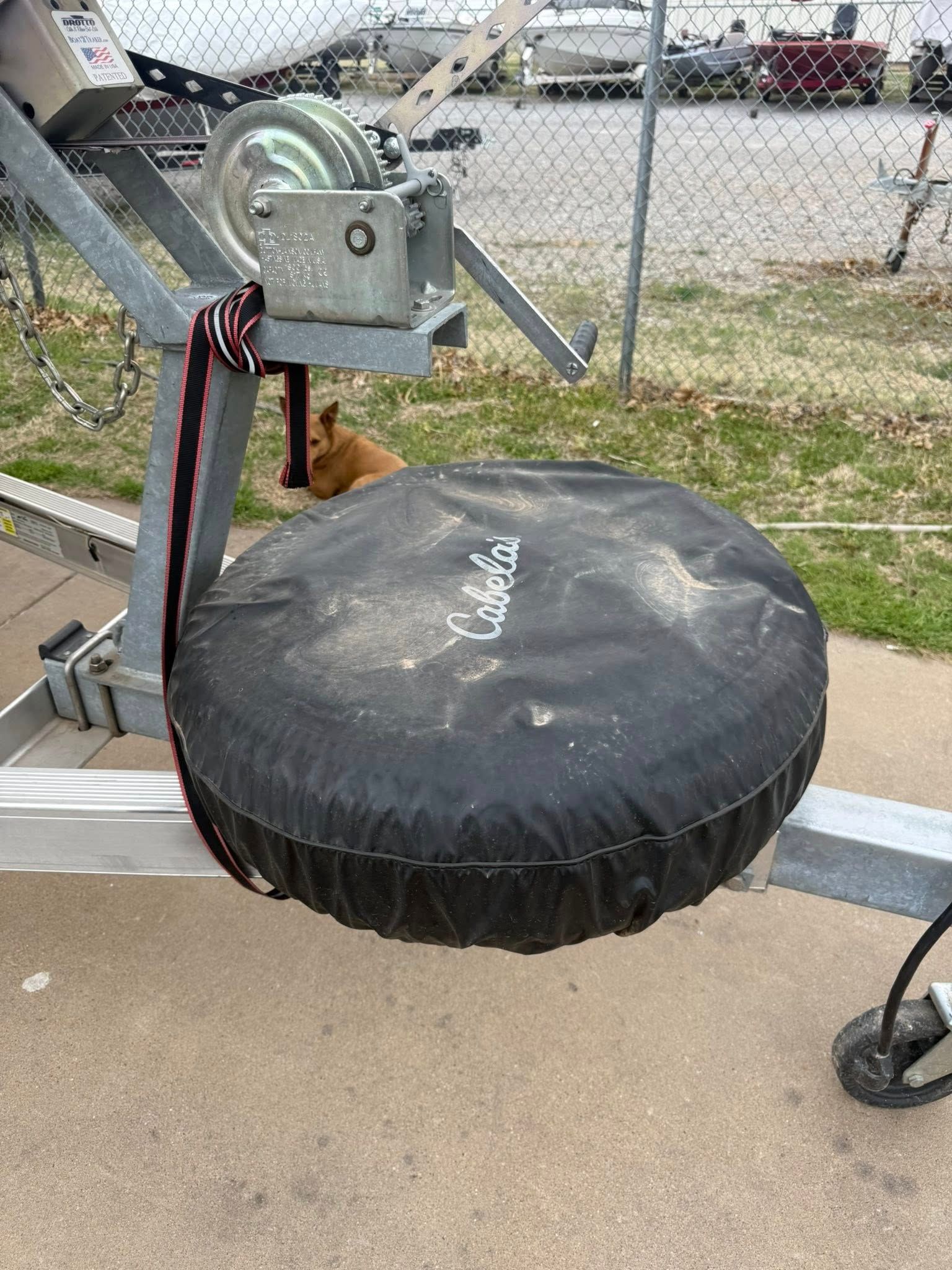 Black padded circular seat attached to a metal lift mechanism on a concrete surface outdoors