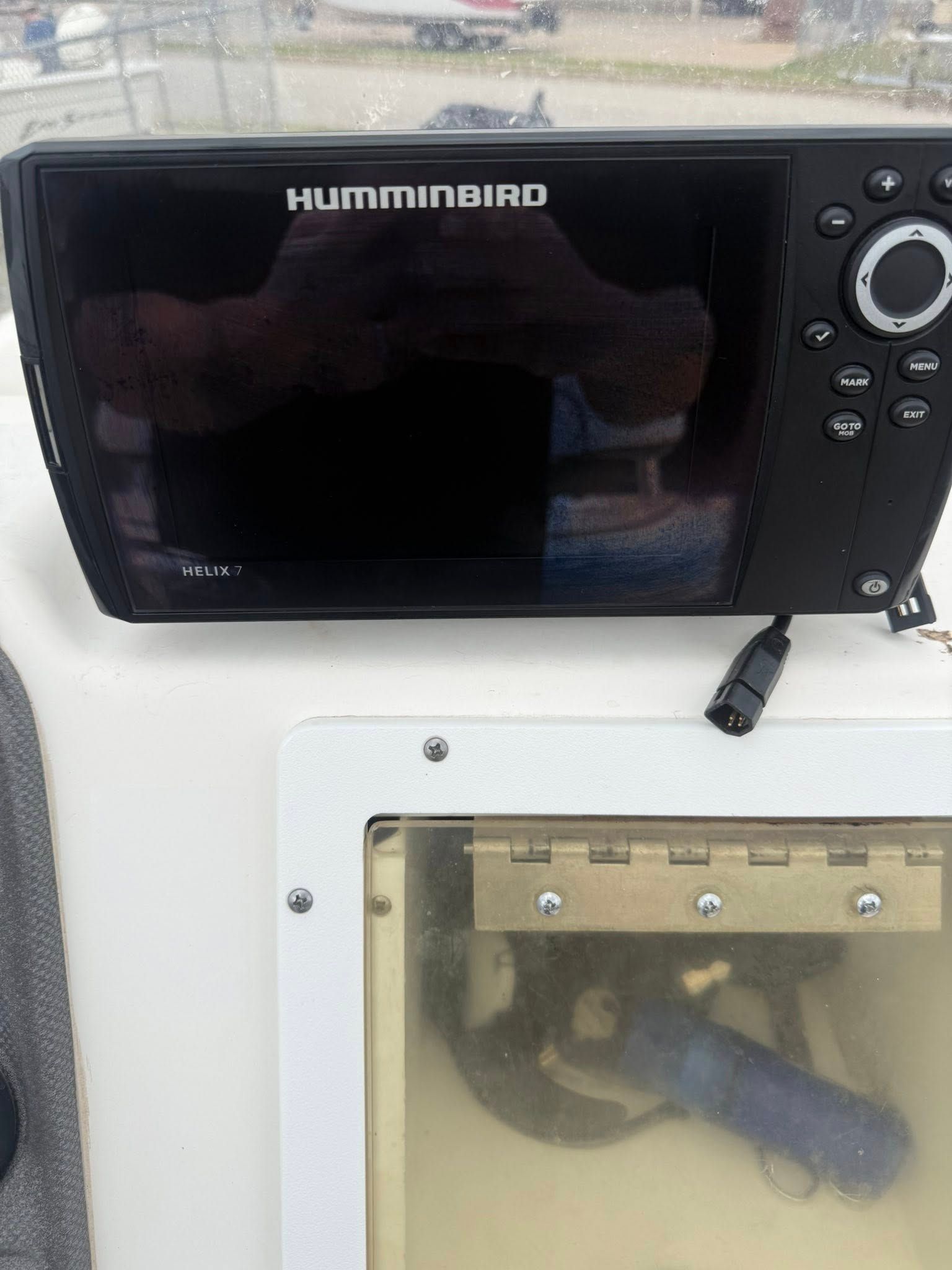 Humminbird marine sonar display beside a mounted electronics compartment on a boat console