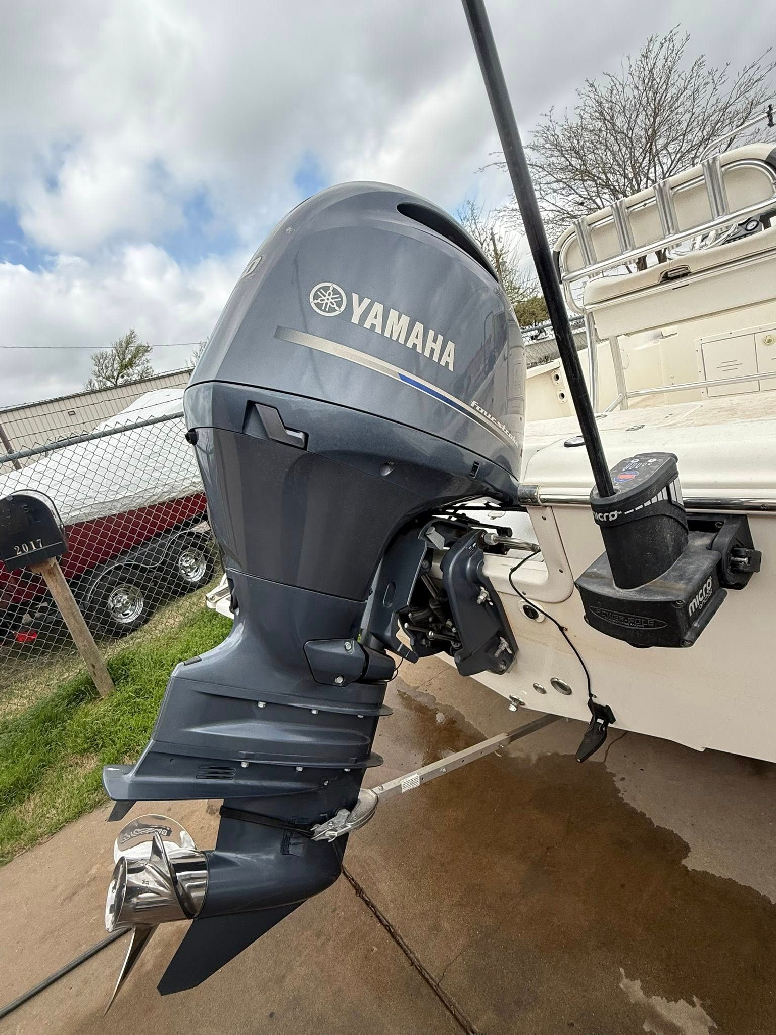 Yamaha outboard motor mounted on a boat stern beside a dock, with dark blue propeller and white hull