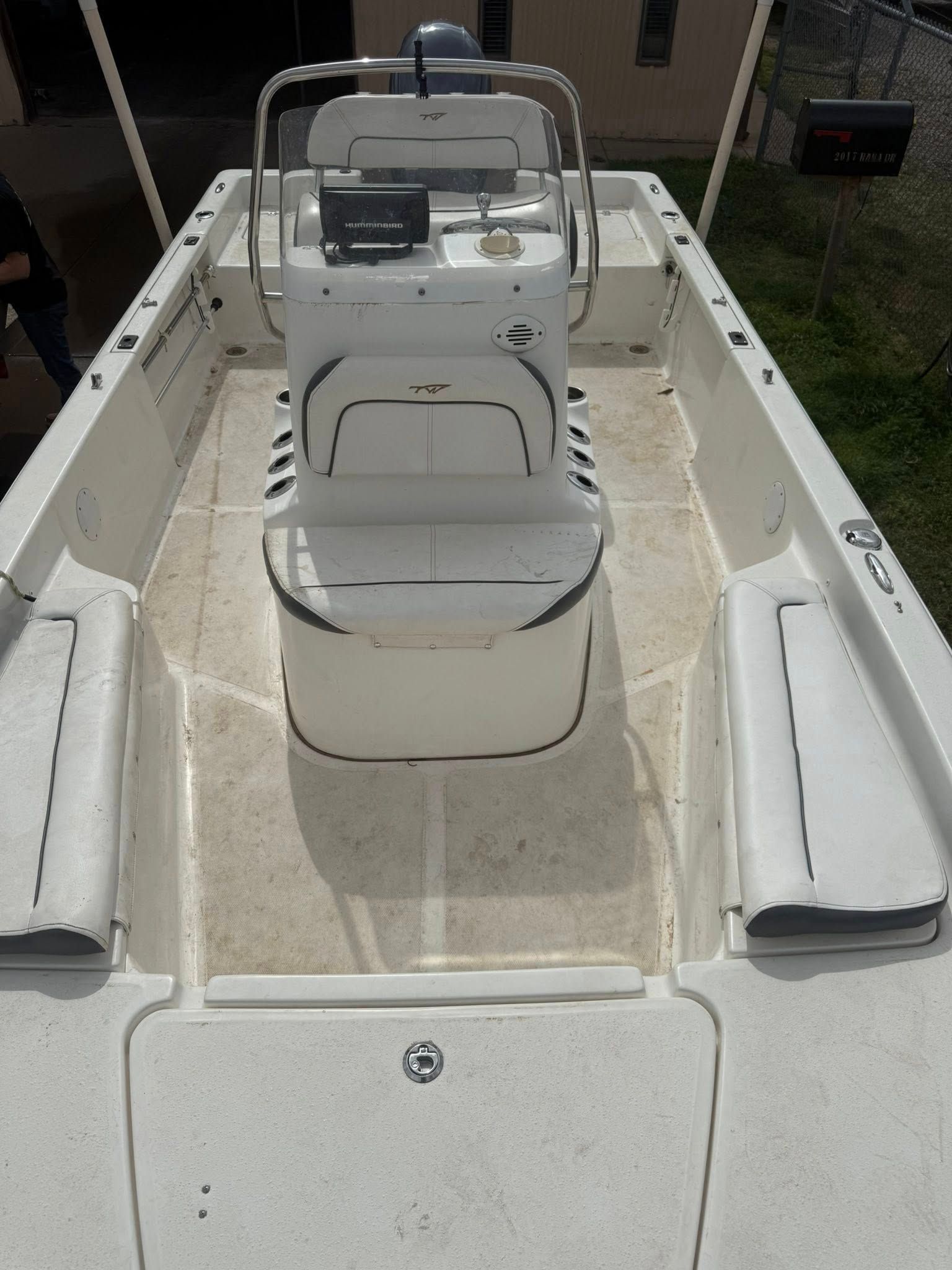 Empty white fishing boat deck with center console and seating, viewed from the stern
