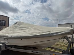 Covered white boat on a trailer under a cloudy sky