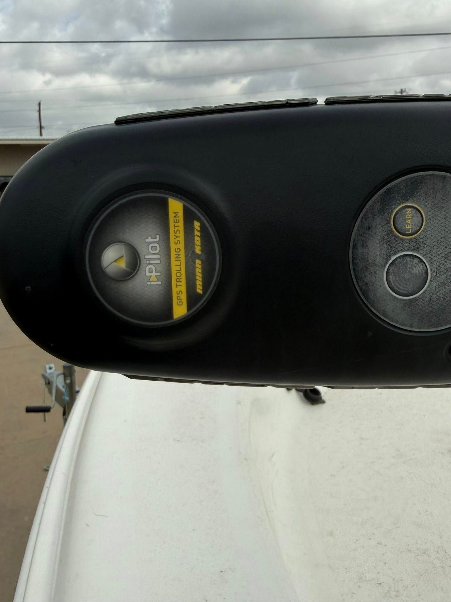 Close-up of a black device with a round yellow label mounted on a white surface outdoors.
