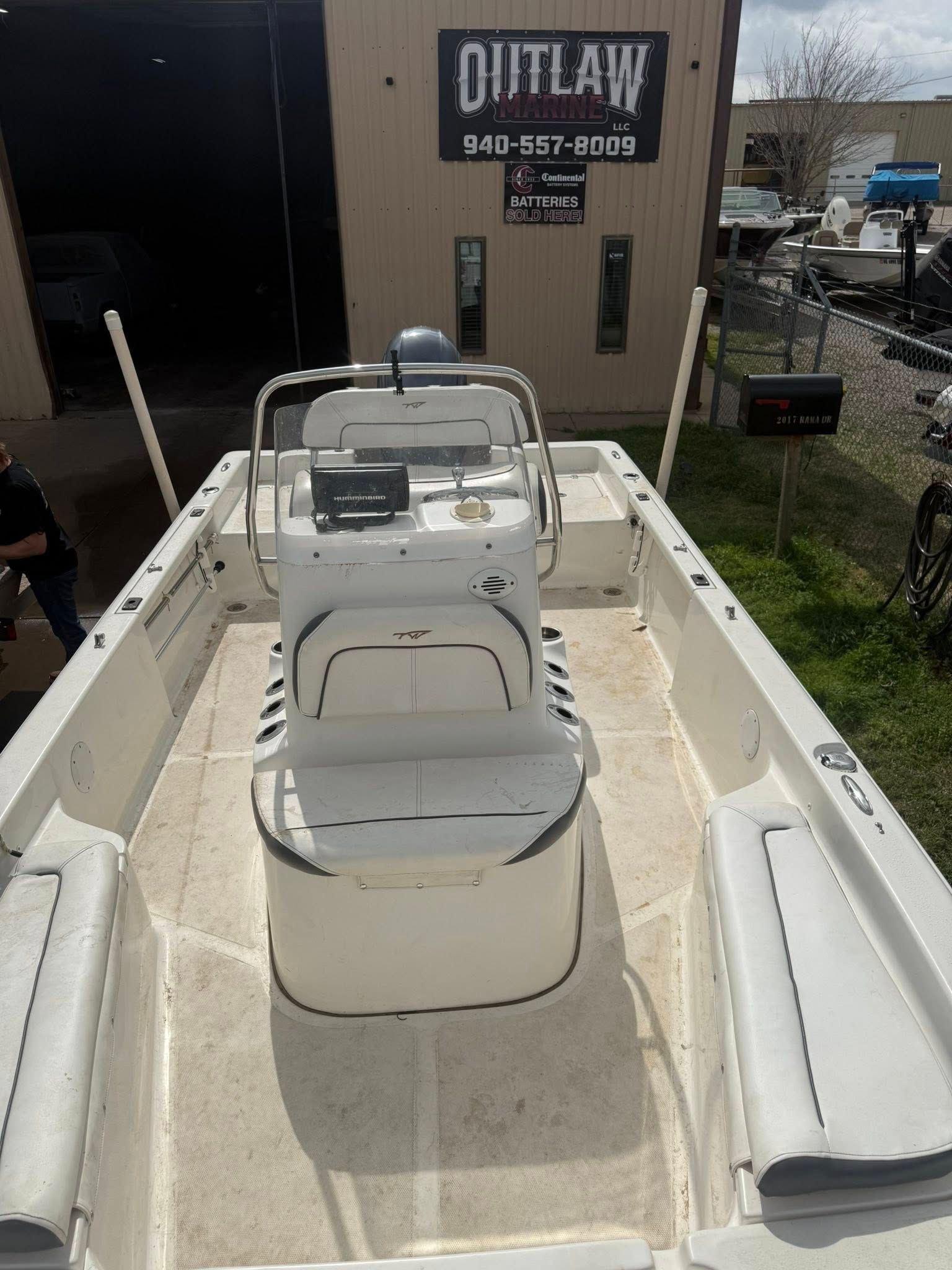 Small white boat interior with center console seats, docked beside an Outlaw building.