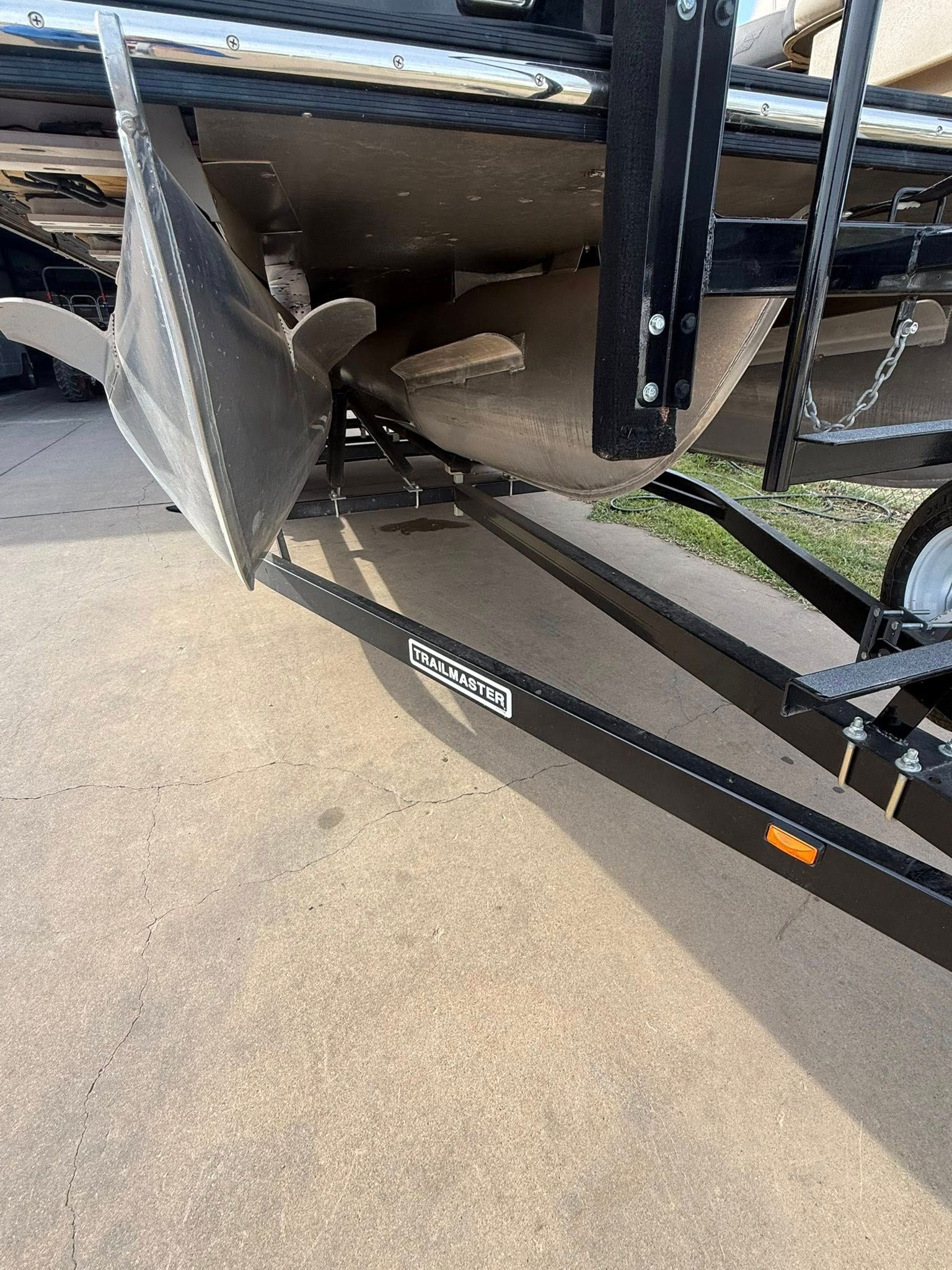 Damaged trailer hitch and bent metal undercarriage near a parking lot curb