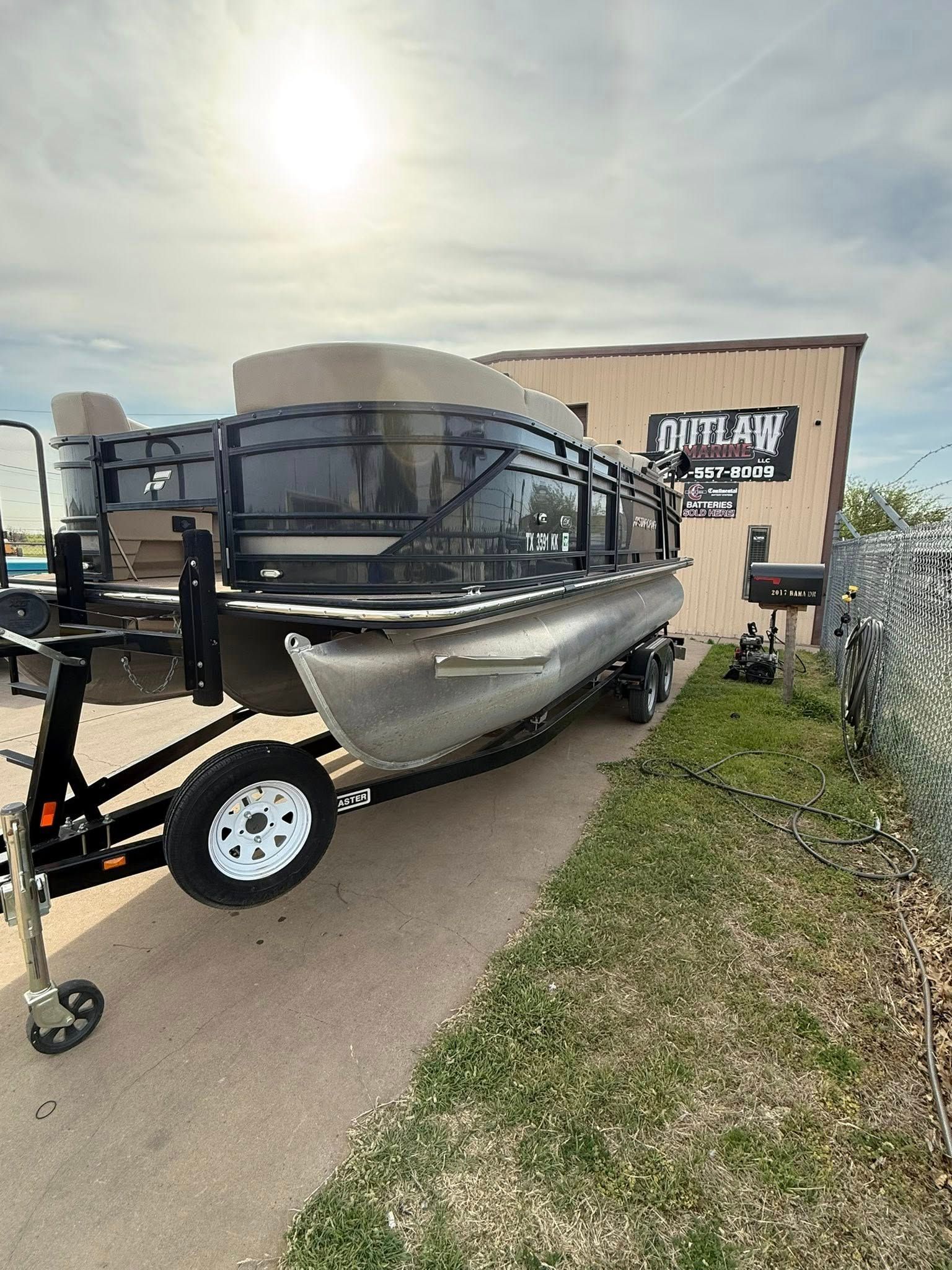 Black boat on a trailer parked outside a shop on a sunny day