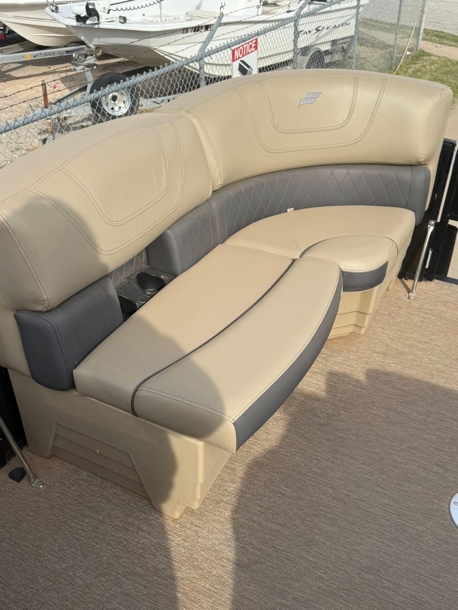 Tan and gray curved boat bench seat on a docked vessel, with marina water in the background