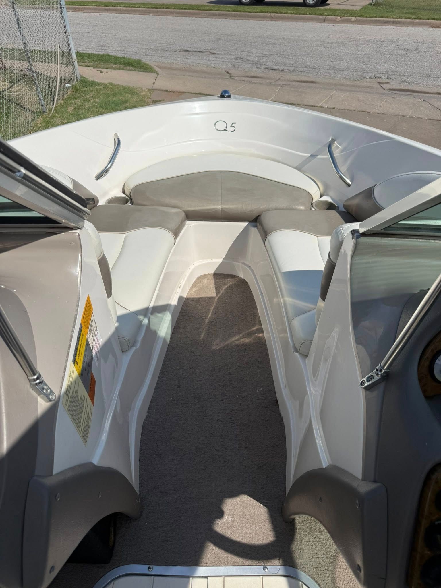View from a boat cockpit with white seats, center passage, and open windshield on a sunny day