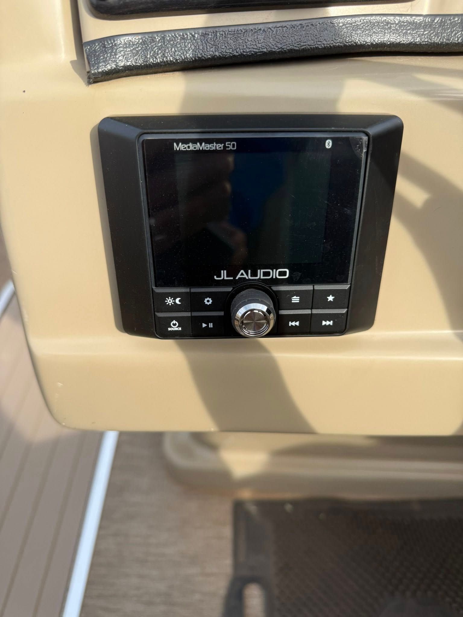 Black JL Audio marine stereo mounted on a beige dashboard panel