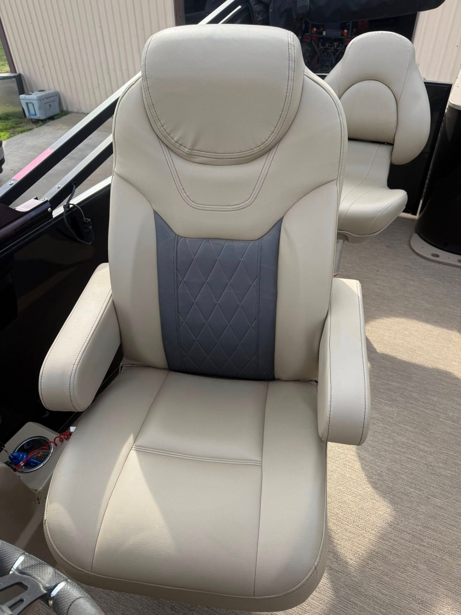 Beige captain’s chair with gray center panel on a boat deck, with a second seat behind it.
