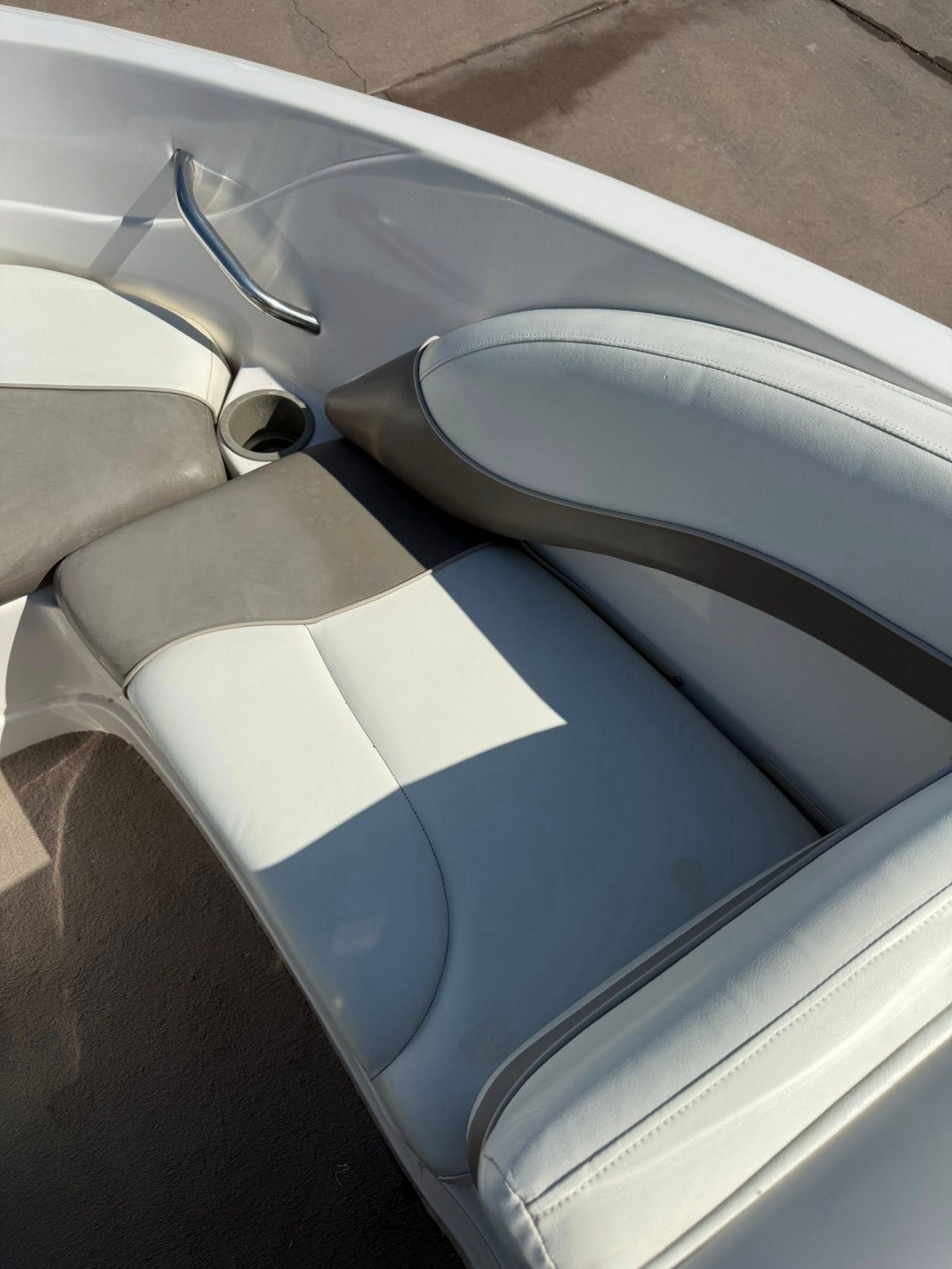Gray and white boat seats with a pair of clear sunglasses resting near the cushion edge