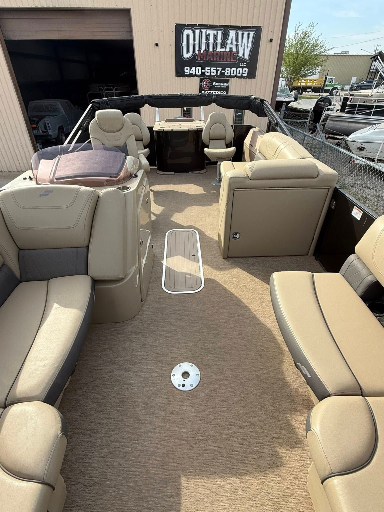 Beige outdoor patio furniture arranged on a dealership lot beside an open garage.