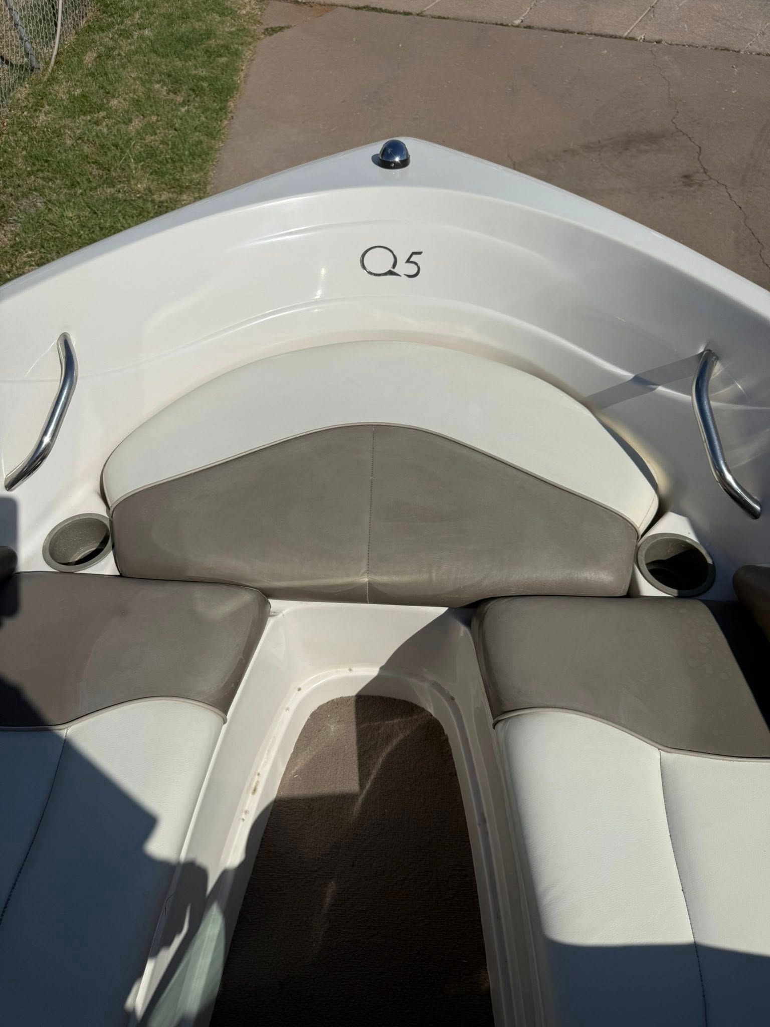 Front bow of a white Q5 boat with gray cushions on the water.