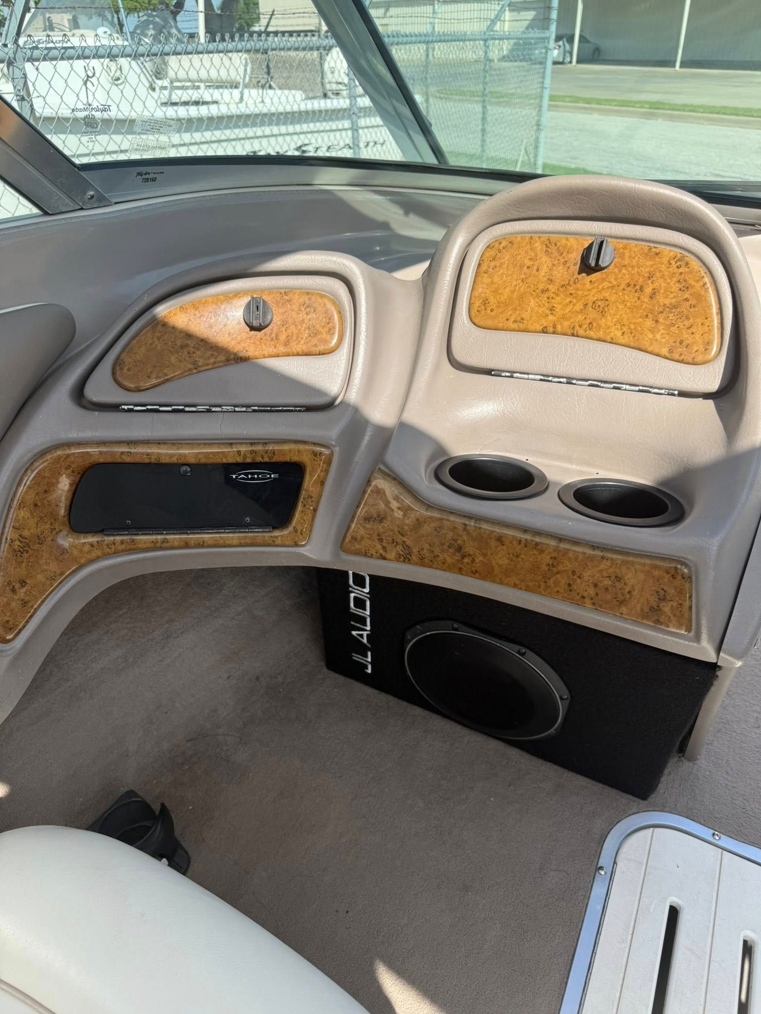 Car interior with gray and tan custom dashboard, cupholders, and a carpeted cabin area