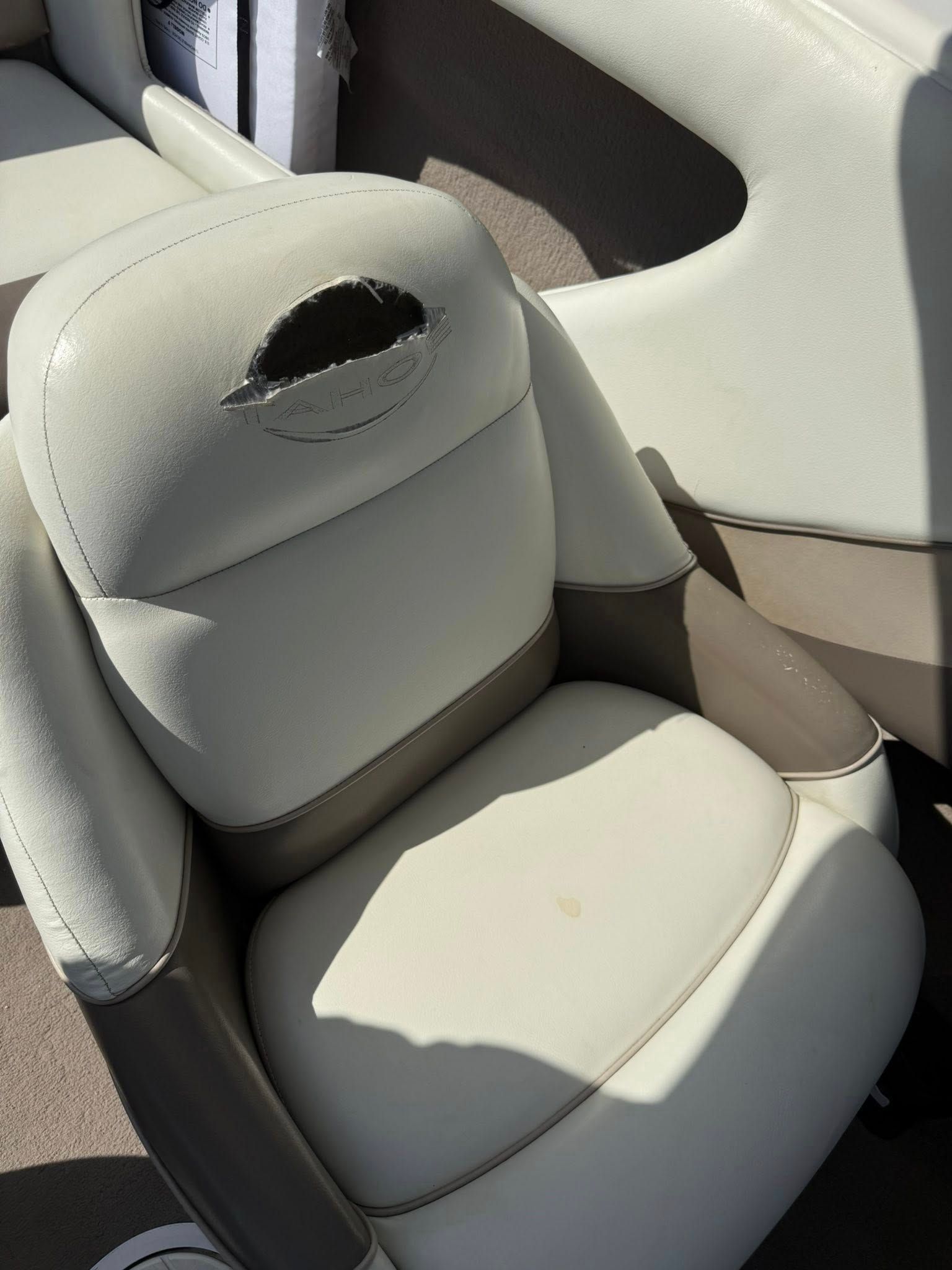 Light gray car seat with a damaged headrest and a torn opening near the top