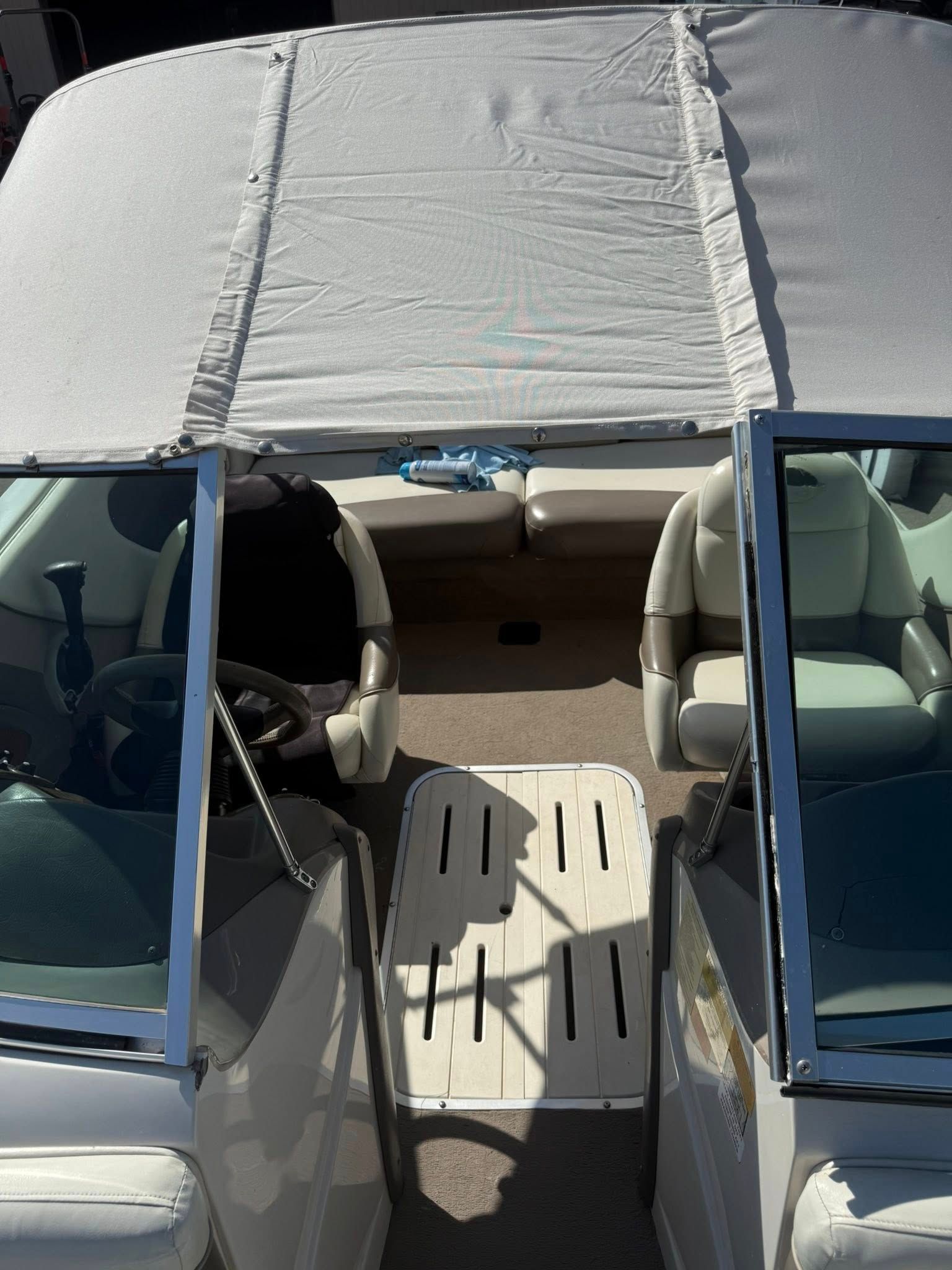 Car interior with blue doors open, front seats visible, and a silver sunshade covering the windshield.