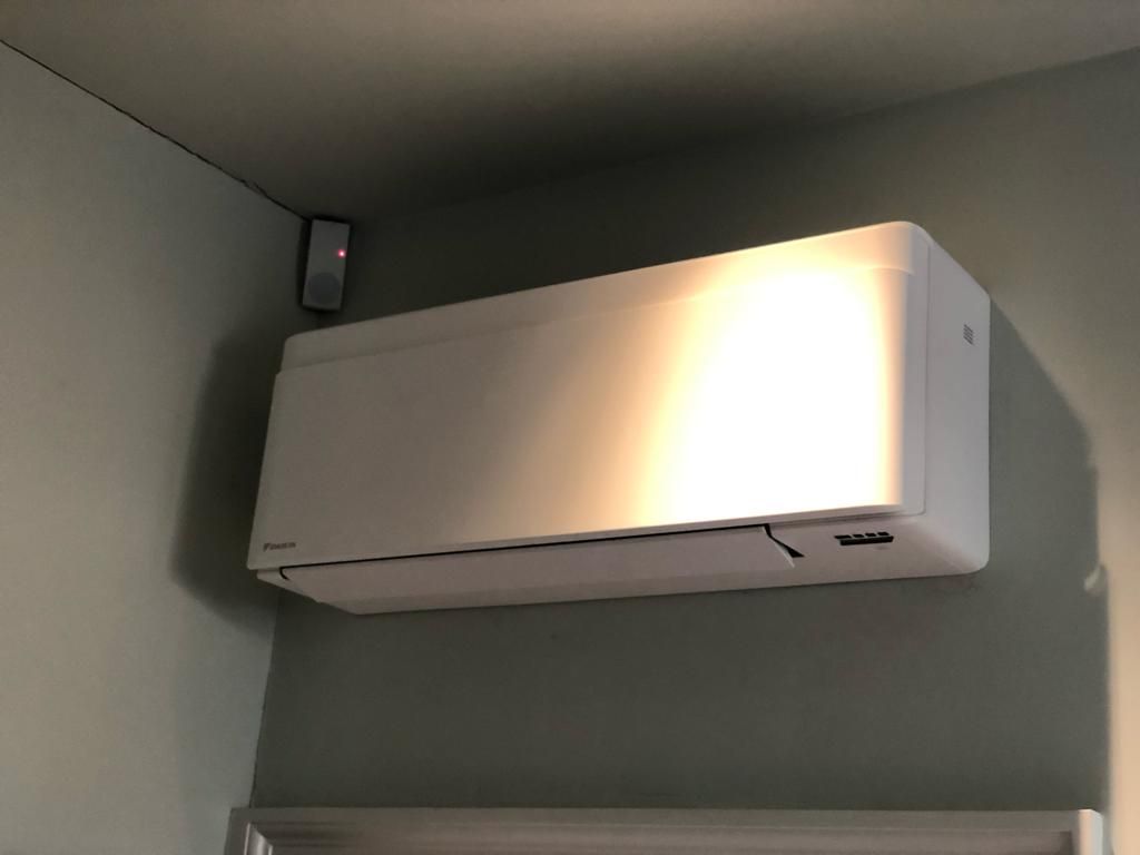 A white air conditioner is hanging from the ceiling in a room.