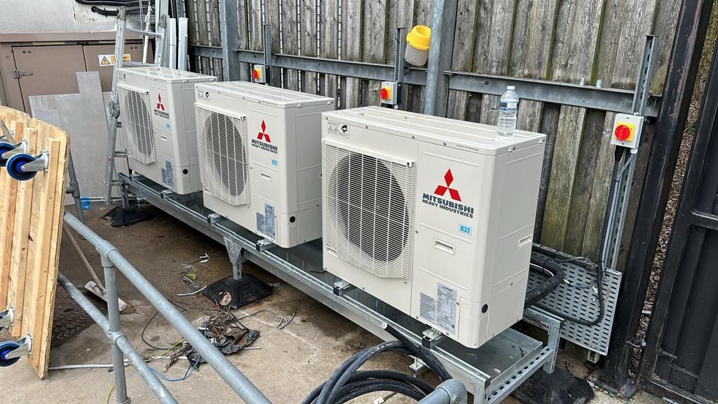A row of air conditioners sitting on top of a metal shelf.