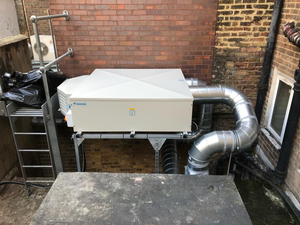 A large white box is sitting in front of a brick building.