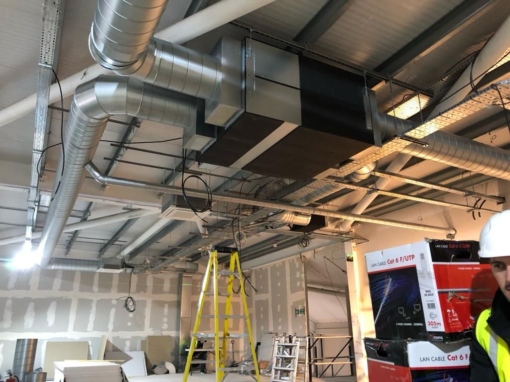 A man is standing in a room with a lot of pipes hanging from the ceiling.