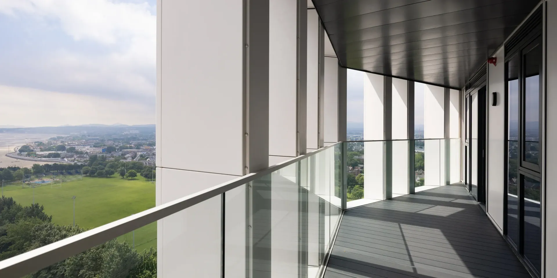 Balcony with glass railing overlooking a green landscape and distant city skyline